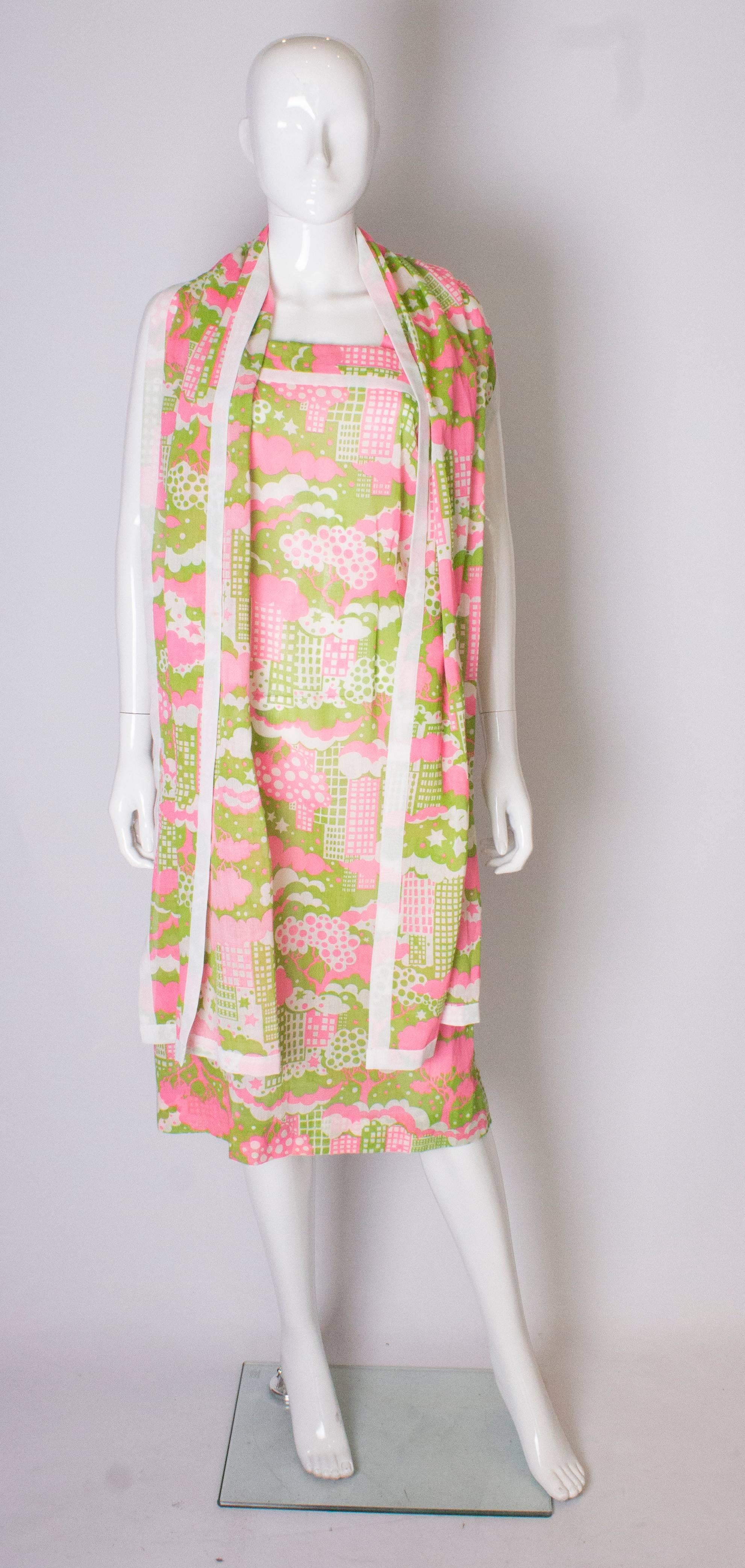 A fun  vintage abstract print  sundress with matching scarf. The dress is a print of pink, white and sage green ,  with a white trim.  It has two straps and a central back zip.
The scarf is the same fabric and measures 88'' x 18''.