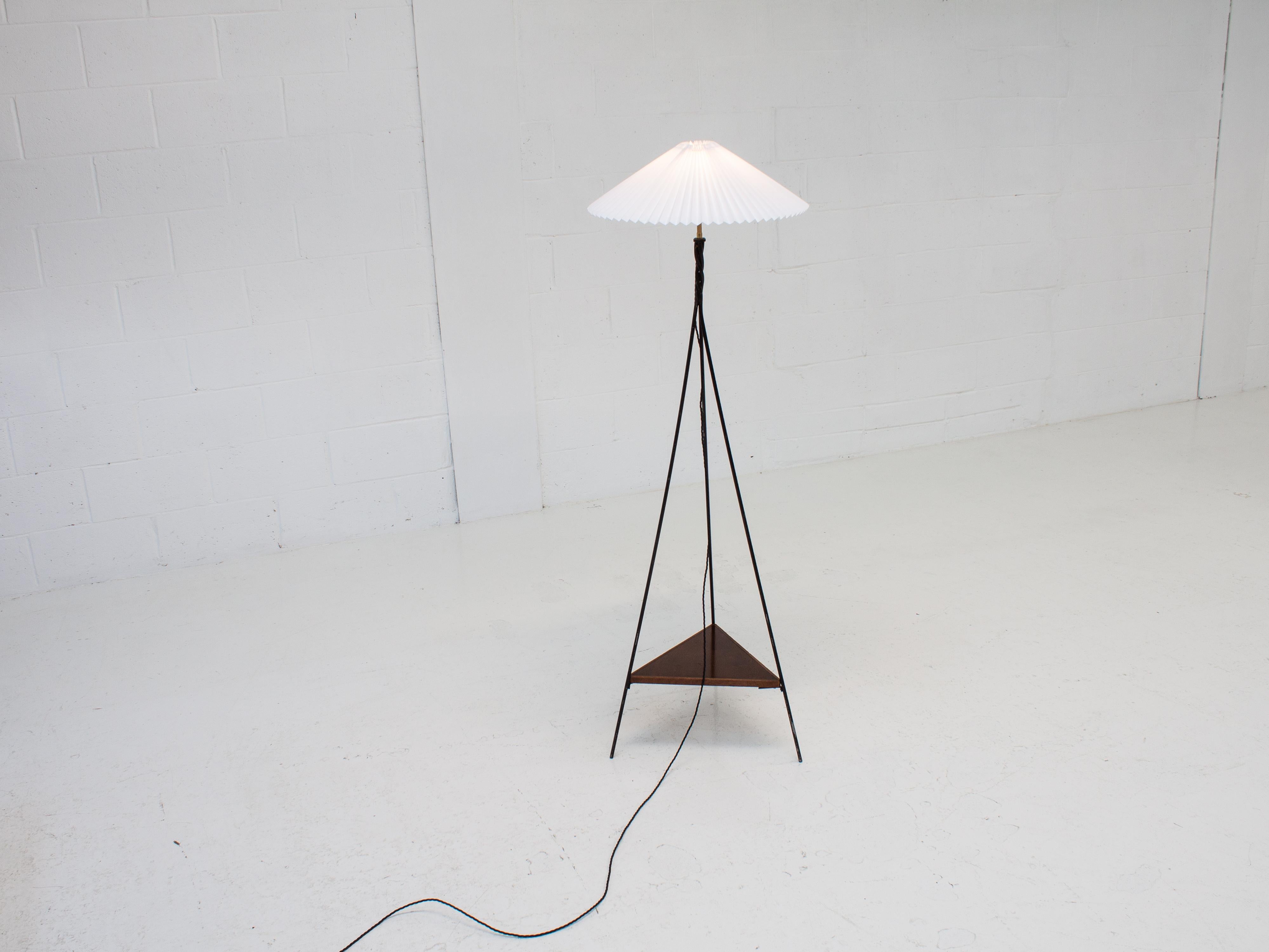 A vintage 1960s floor lamp, consisting of a triangular three-rod base which has a twisted finish housing the bulb holder fittings, the stand also has a walnut wooden tier and pleated shade and has been fully rewired using fabric braided black flex