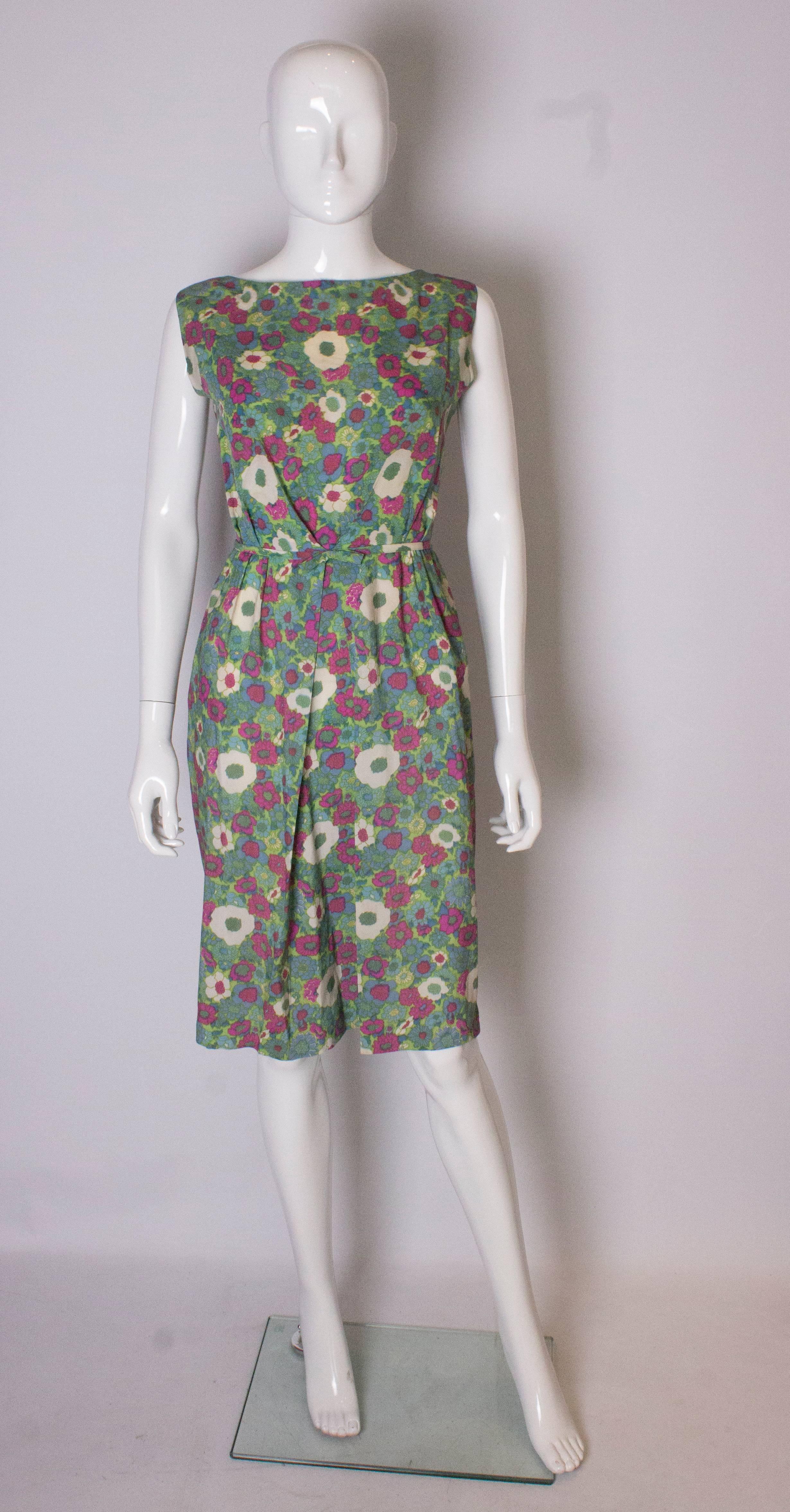 Un bonito vestido vintage para primavera/verano, con estampado floral verde, burdeos, azul y crema. El vestido tiene un pliegue y un fruncido en la parte delantera con un  reverencia. Se abre por detrás con 5 botones y 3 automáticos.