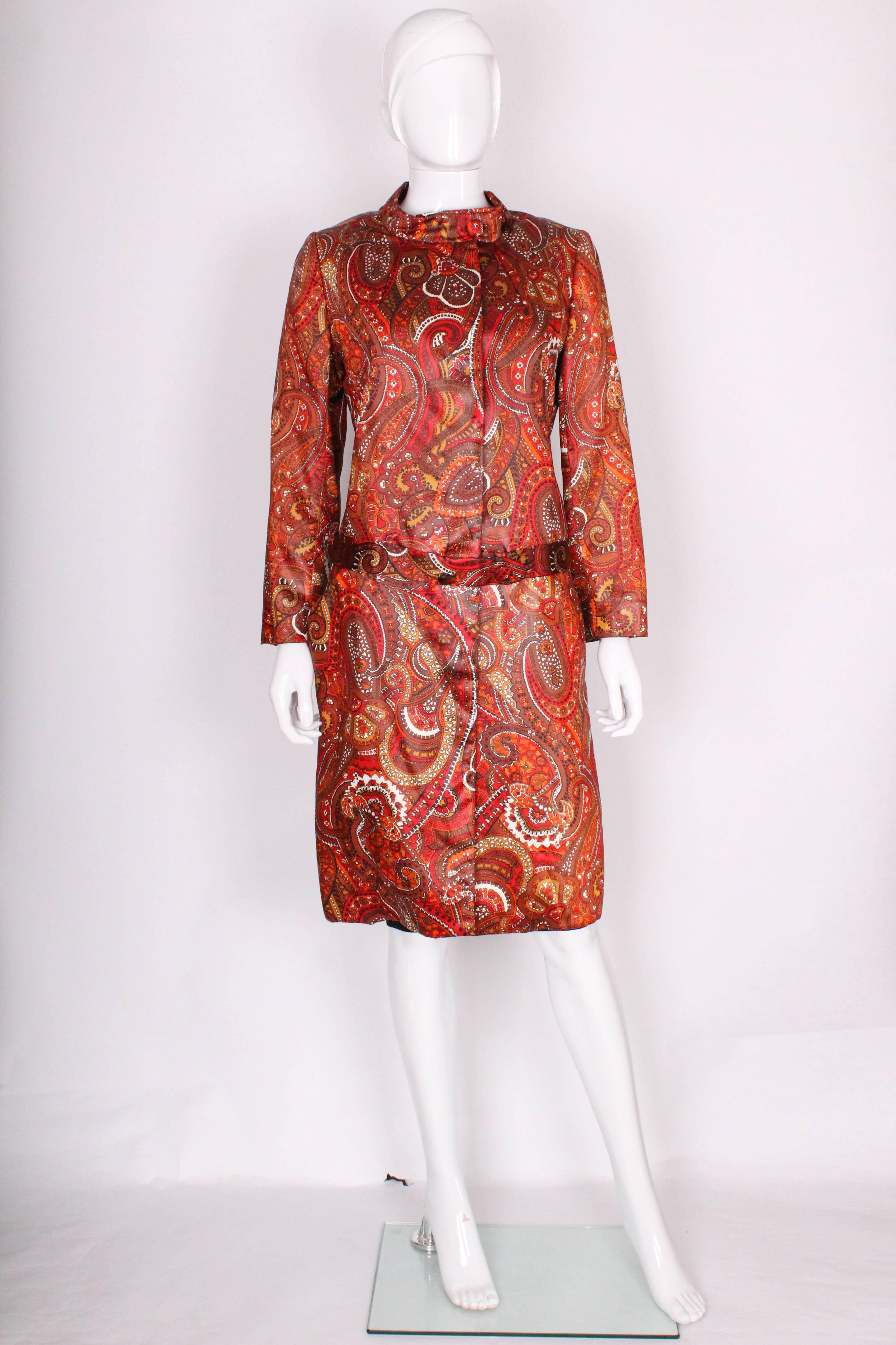 A great coat for fall from American designer Bill Blass.
In a wonderful paisley print ,and fall colours of red, orange, white, brown and bronze.This coat is loose fitting with a mandarin collar with buttons at the neck, a 4 button fastening, two