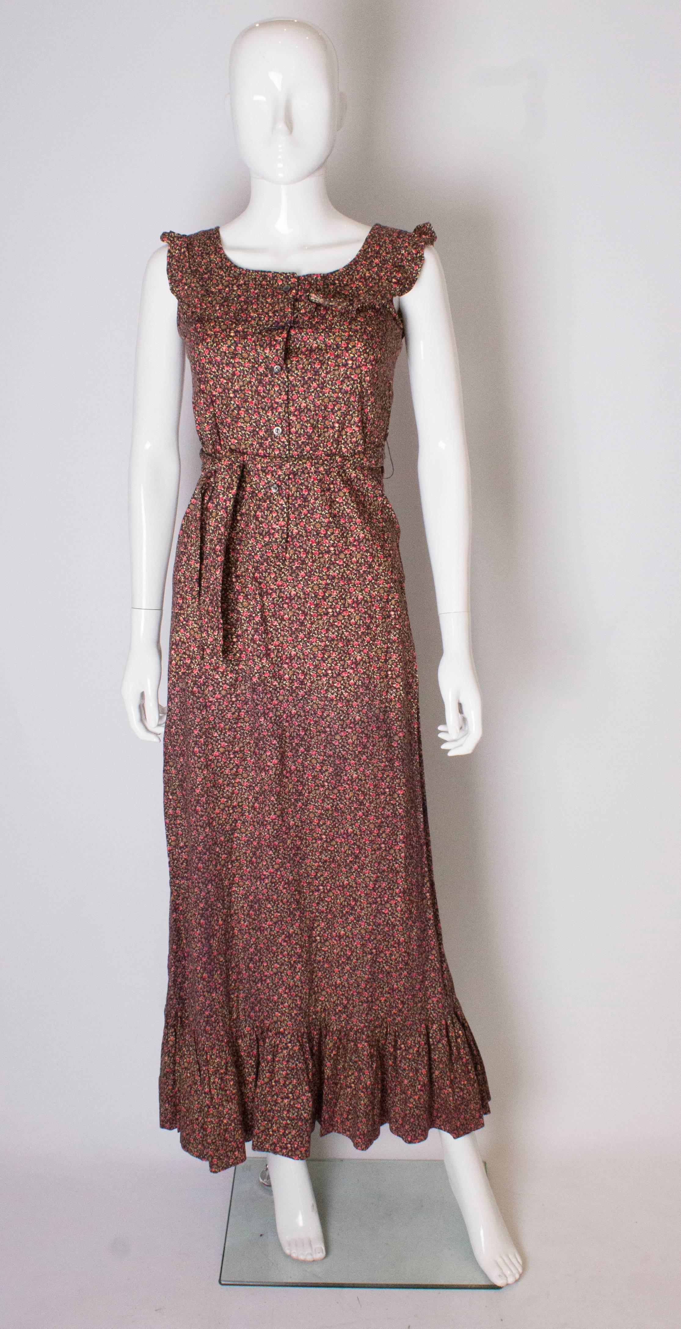 A great vintage dress for summer, and festivals This long floral  cotton gown by Quad has a frill around the neckline and hem , a front button opening, and self fabric tie belt. 