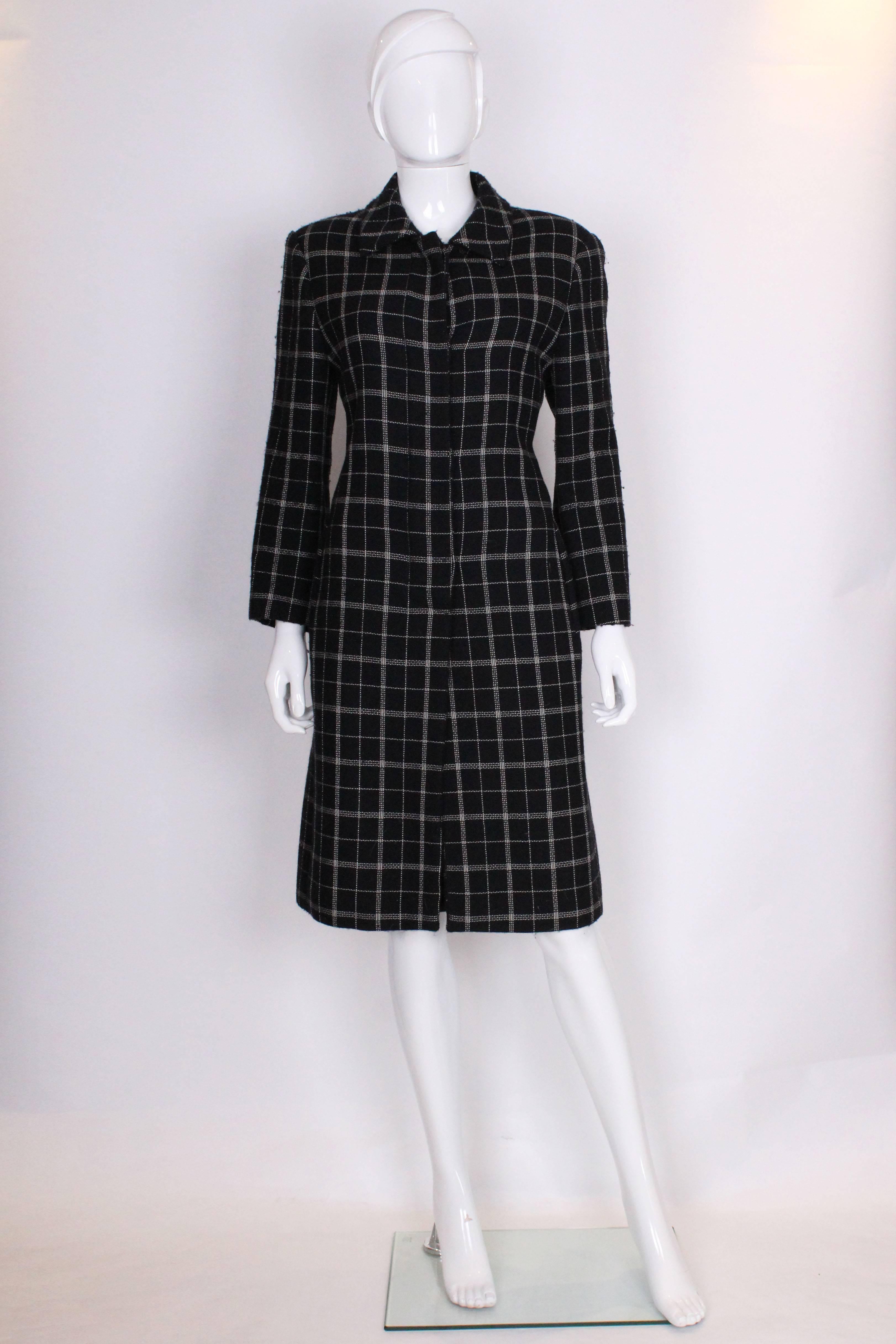 A chic and easy to wear coat by Oleg Cassini Couture.The coat has a black background with a white line pattern, horizontal and vertical.It has a 4 button closure ,is unlined , has a vent at the back and a pocket on each side.