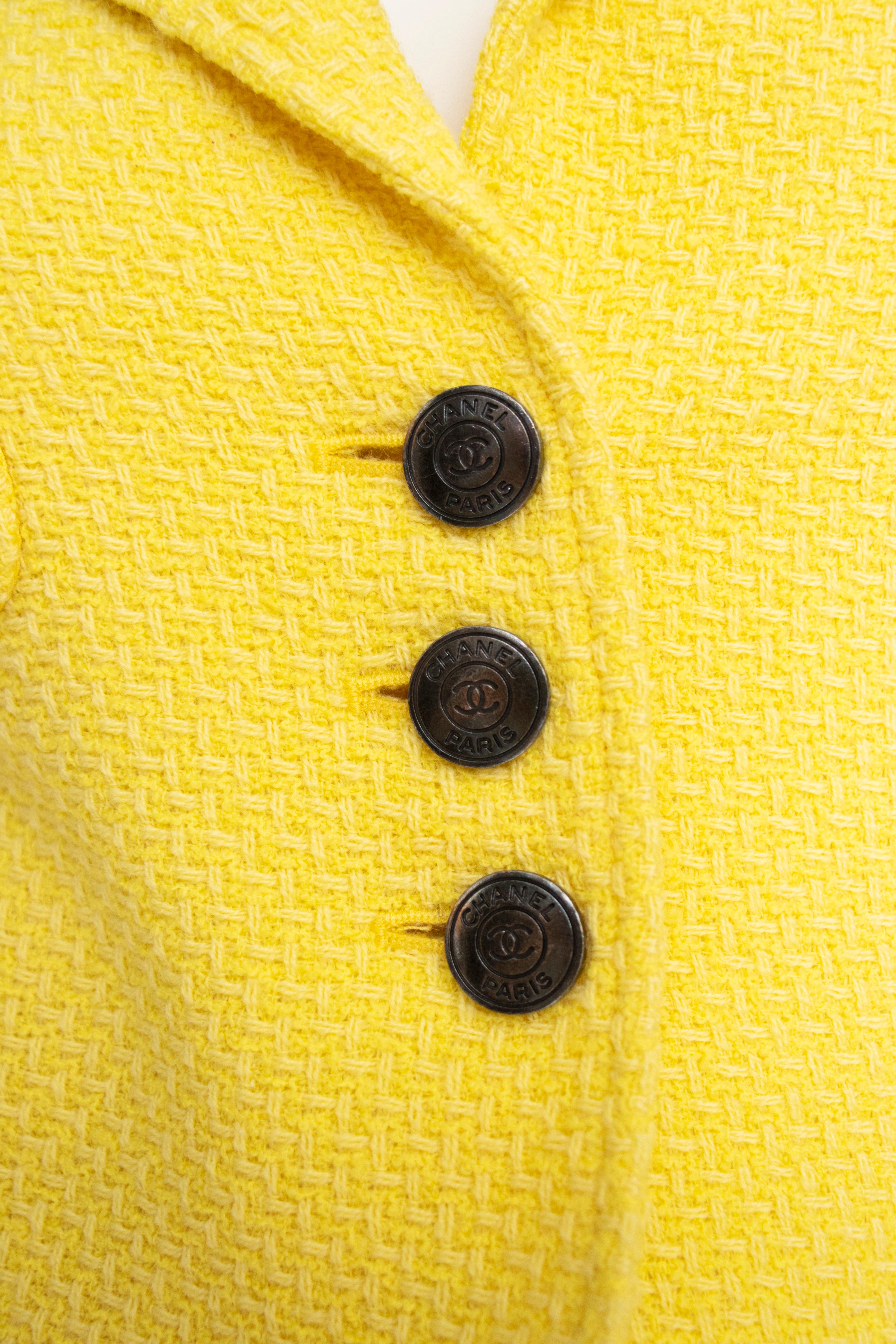 A vintage Chanel skirt suit from the 1997s Cruise Collection consisting of a fitted pencil skirt and a cropped jacket with Chanel embossed logo buttons.

Both are lined in matching yellow silk and logo woven lining. 