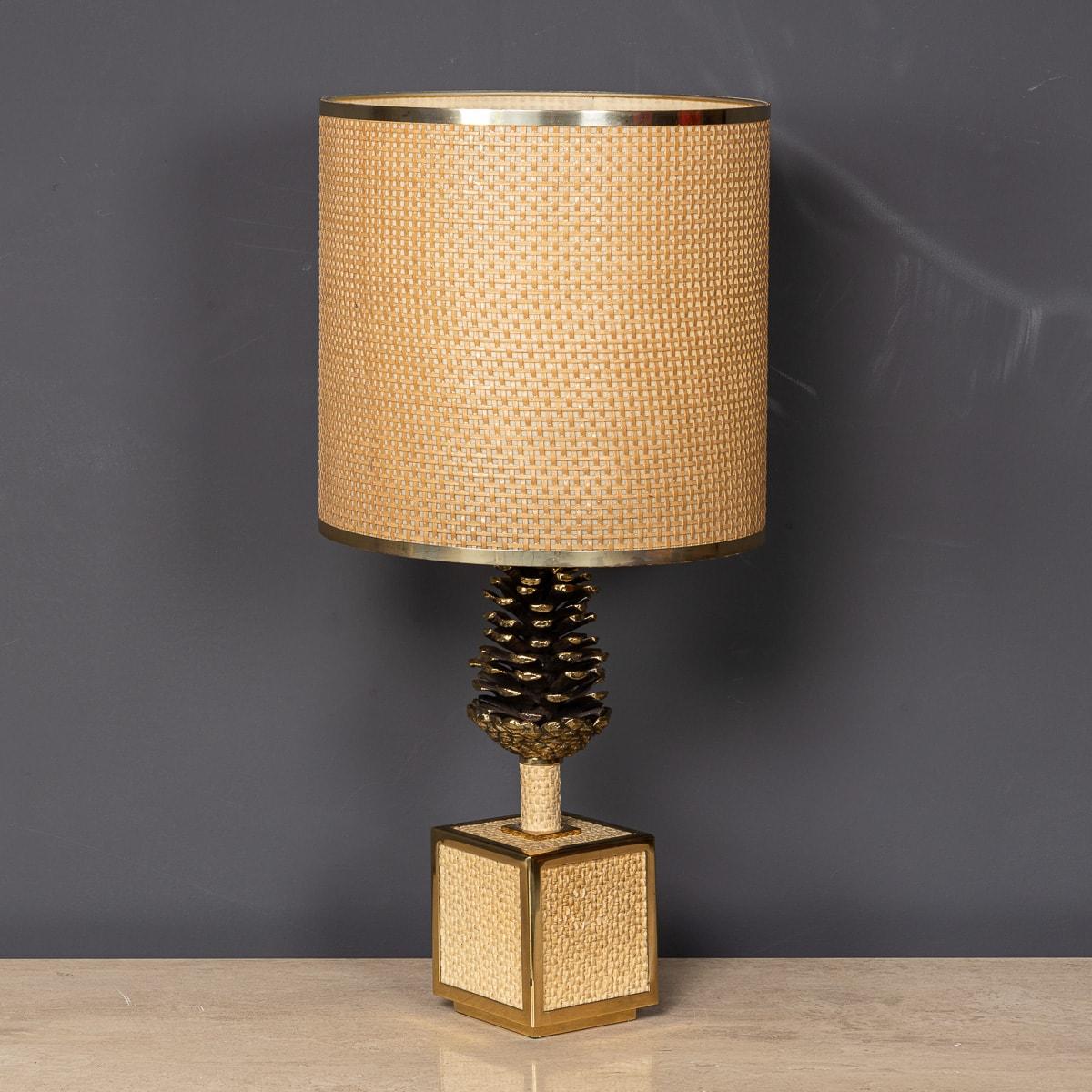 Crafted in the 20th century, this stunning table lamp. Adorned with a metal gilded pine cone atop a square Bergere plinth, accented with brass, it exudes elegance and charm. Its captivating design effortlessly draws the eye, elevating any living
