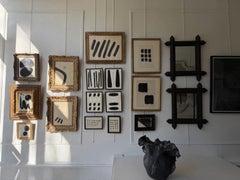 Una obra abstracta vintage en tinta sobre papel, con un marco de madera dorada imitación de bambú