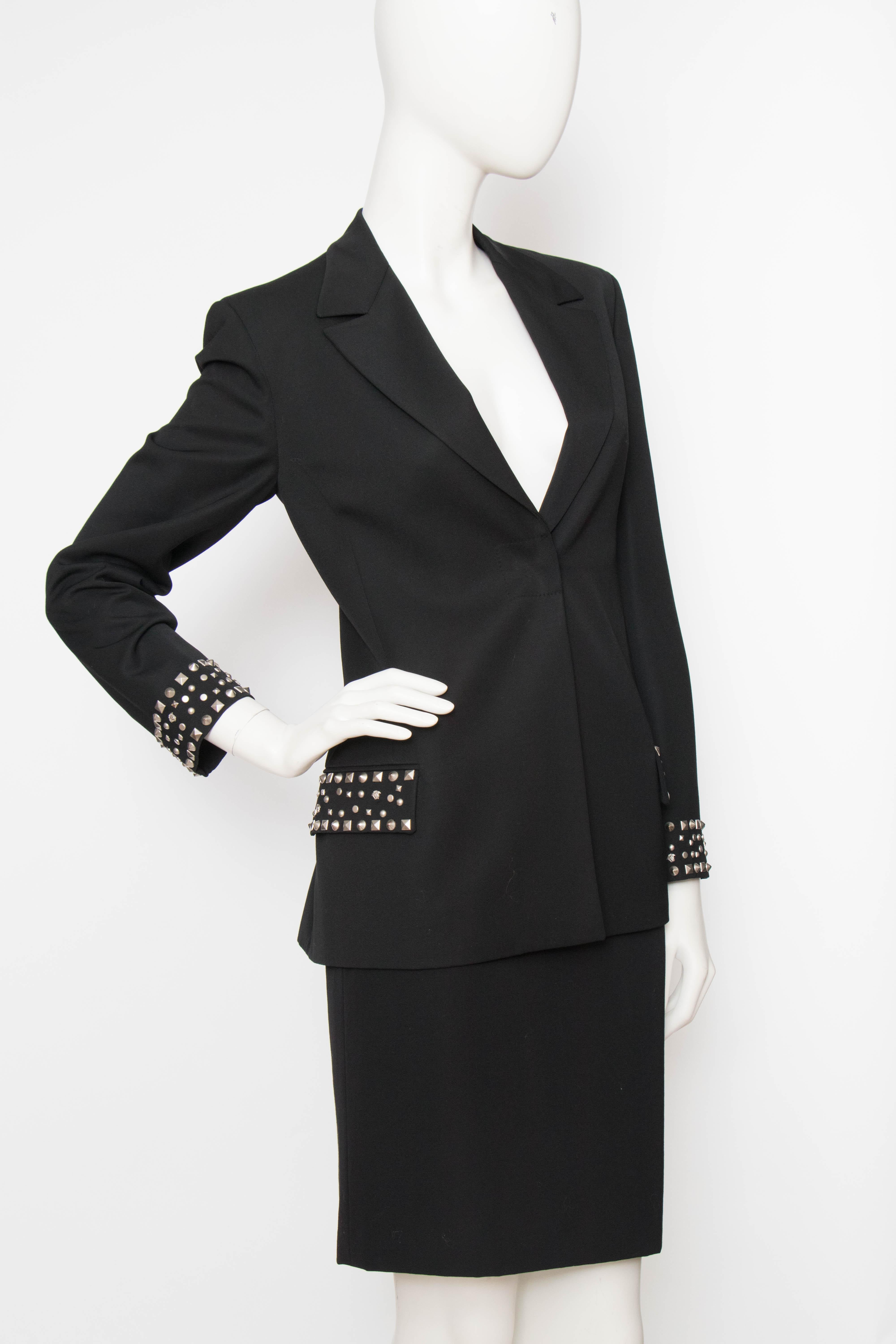 An incredible 1990s Gianni Versace Couture wool skirt suit consisting o a fitted blazer and alluring pencil skirt. The classic garment is embellished with edgy studs in various shapes including Madusa heads. Both items are fully lined in rayon with