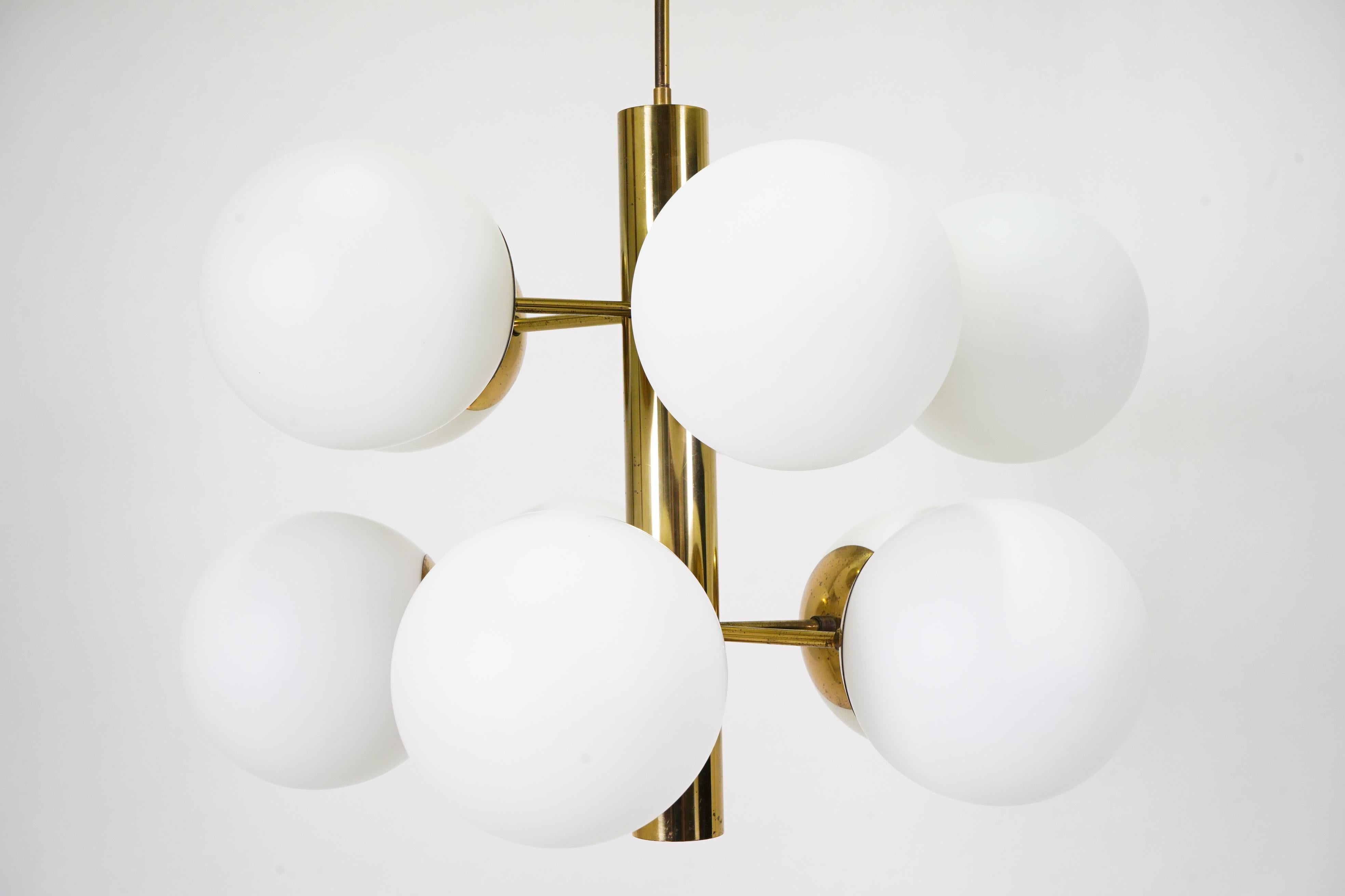This bold and elemental chandelier features solid brass arms and opaline glass globes. The brass has been carefully cleaned of tarnish and the wiring replaced. Part of the canopy is new and designed to fit standard North American ceiling junction