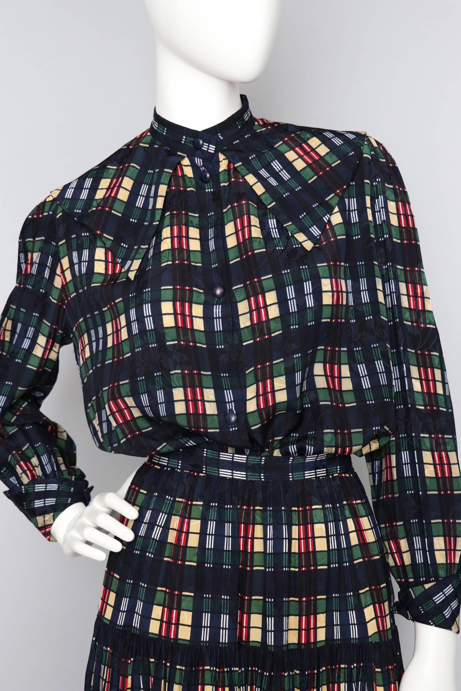 A fabulous 1980s Christian Dior jacquard woven silk ensemble consisting of a pleated skirt and blouse. The blouse has a front button closure, asymmetrical turn-up cuffs, and an exaggerated collar that forms a v-shape at the back. The skirt is fitted