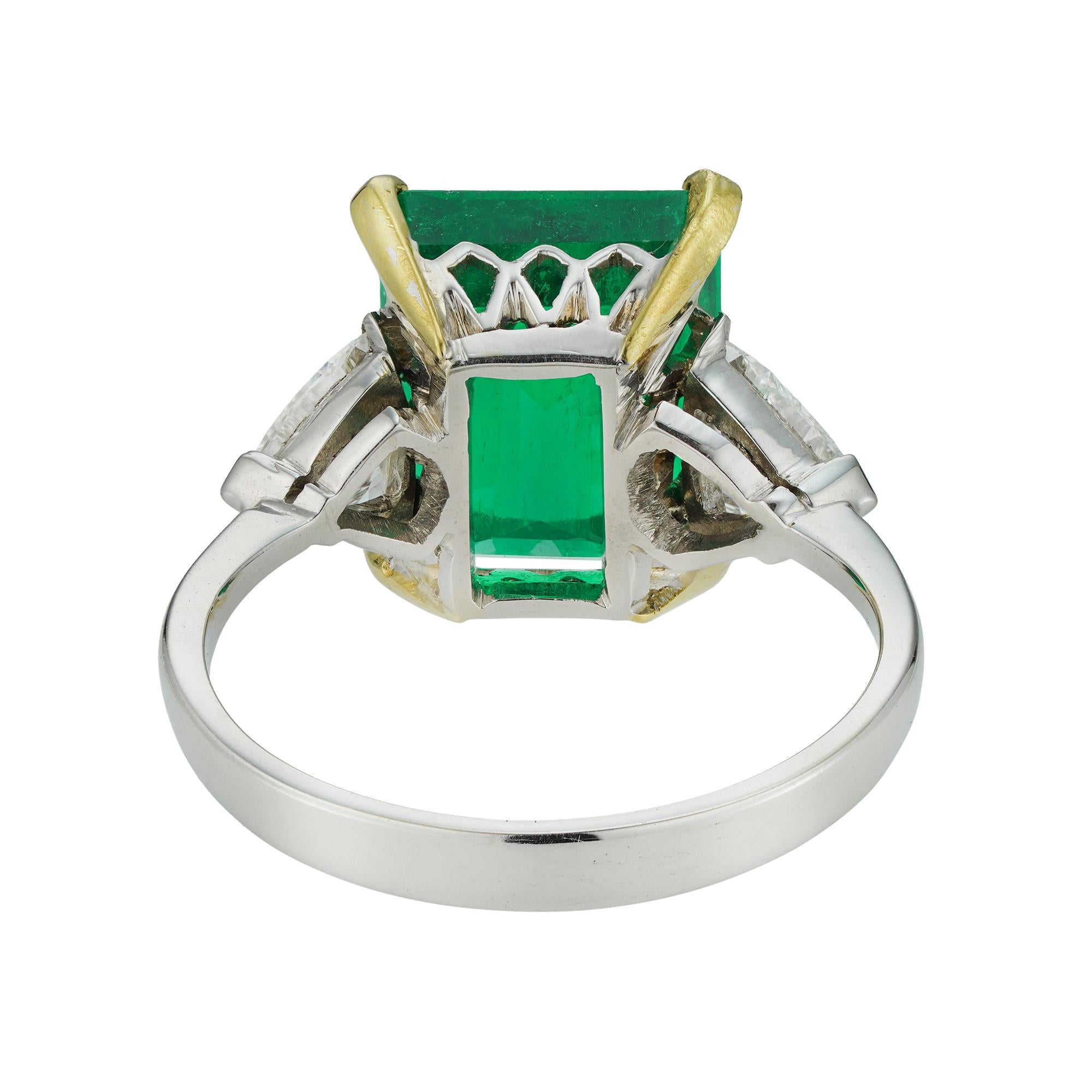 A vintage Colombian emerald and diamond ring, the octagonal-cut emerald weighing 4.41 carats, accompanied by GCS report stating to be of Colombian origin, four claw-set between two trillion-cut diamonds the one weighing 0.35 carats of F colour and