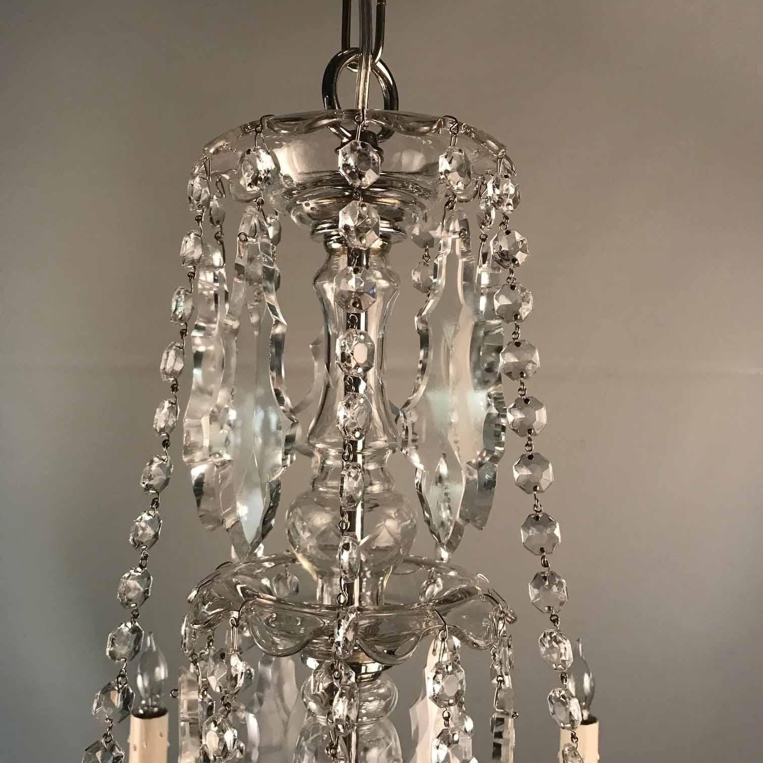 This chandelier is of a date when much handwork was still the norm. The actual glass is unusually brilliant. It is hung with swags of cut beads and decorated with variations of French style pendants. Unusually the central pendant finial is modeled
