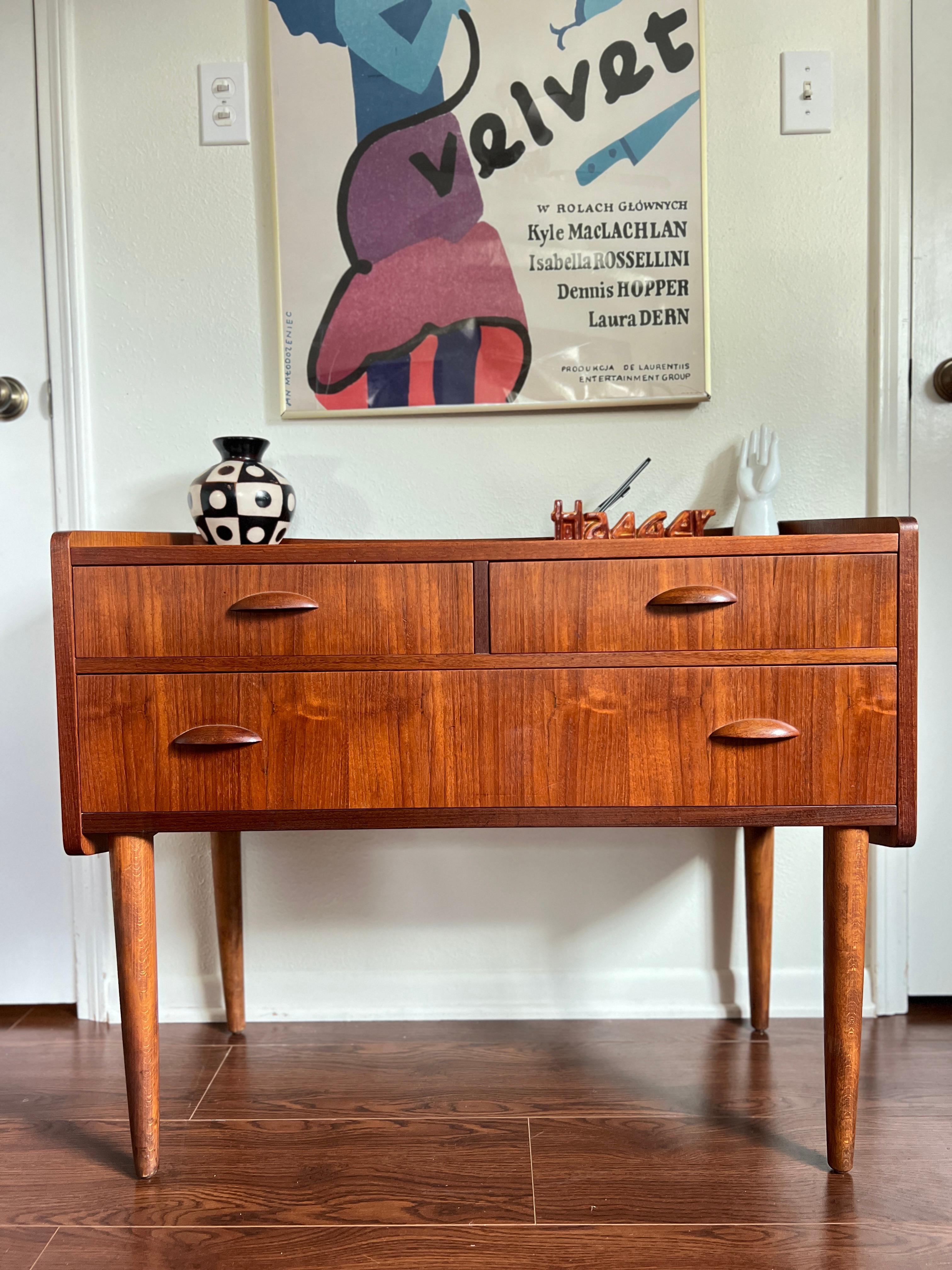 A vintage Danish teak chest or desk with a beautiful teak grain, circa 1960s. This small piece is a perfect size to be used as an accent or entryway table or desk. This chest has 3 drawers with sculpted drawer pulls. Overall in good original