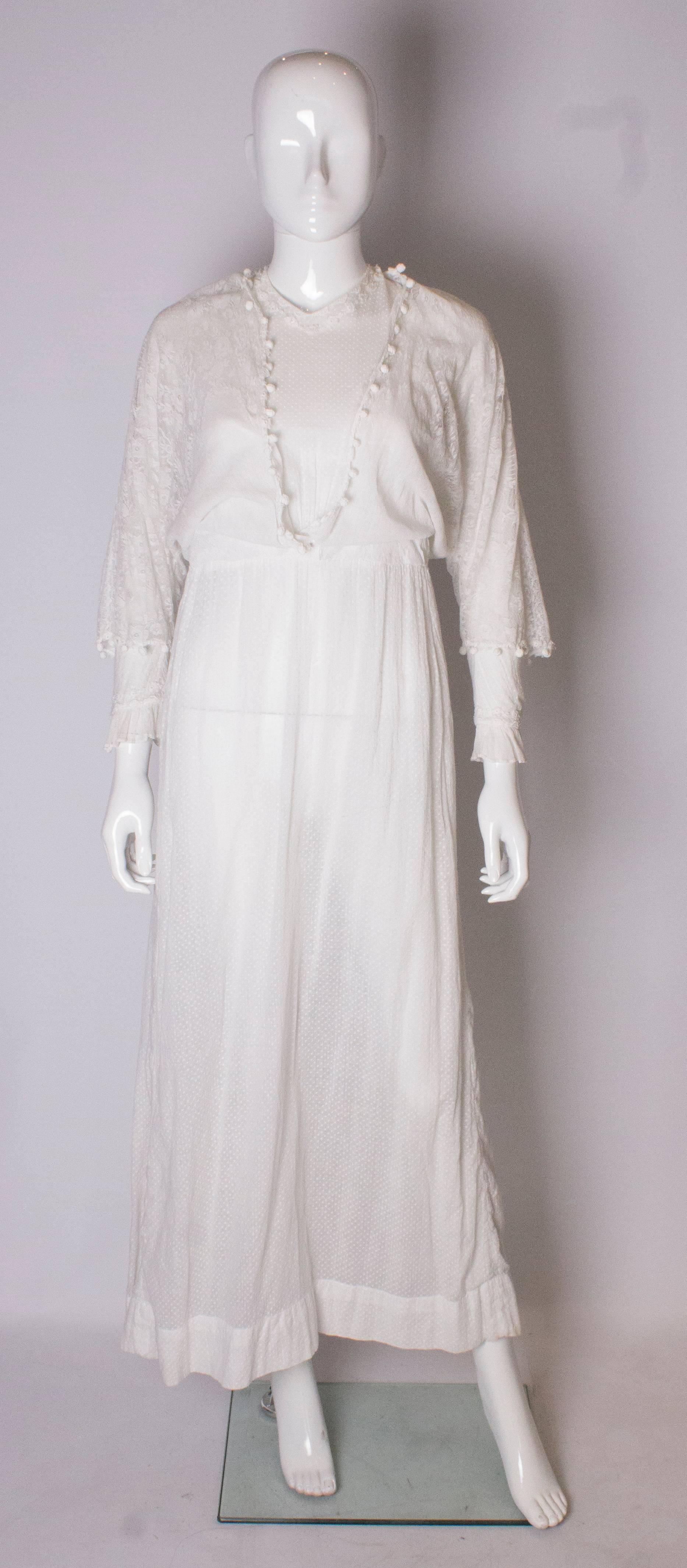 A pretty white Edwardian dress, with cotton spot detail . The dress has lace over the sleeves and bodice front, and back.. The sleeves have a lace detail at the cuffs, and the bodice has a  pleat detail. It fastens with hooks and eyes at the back.