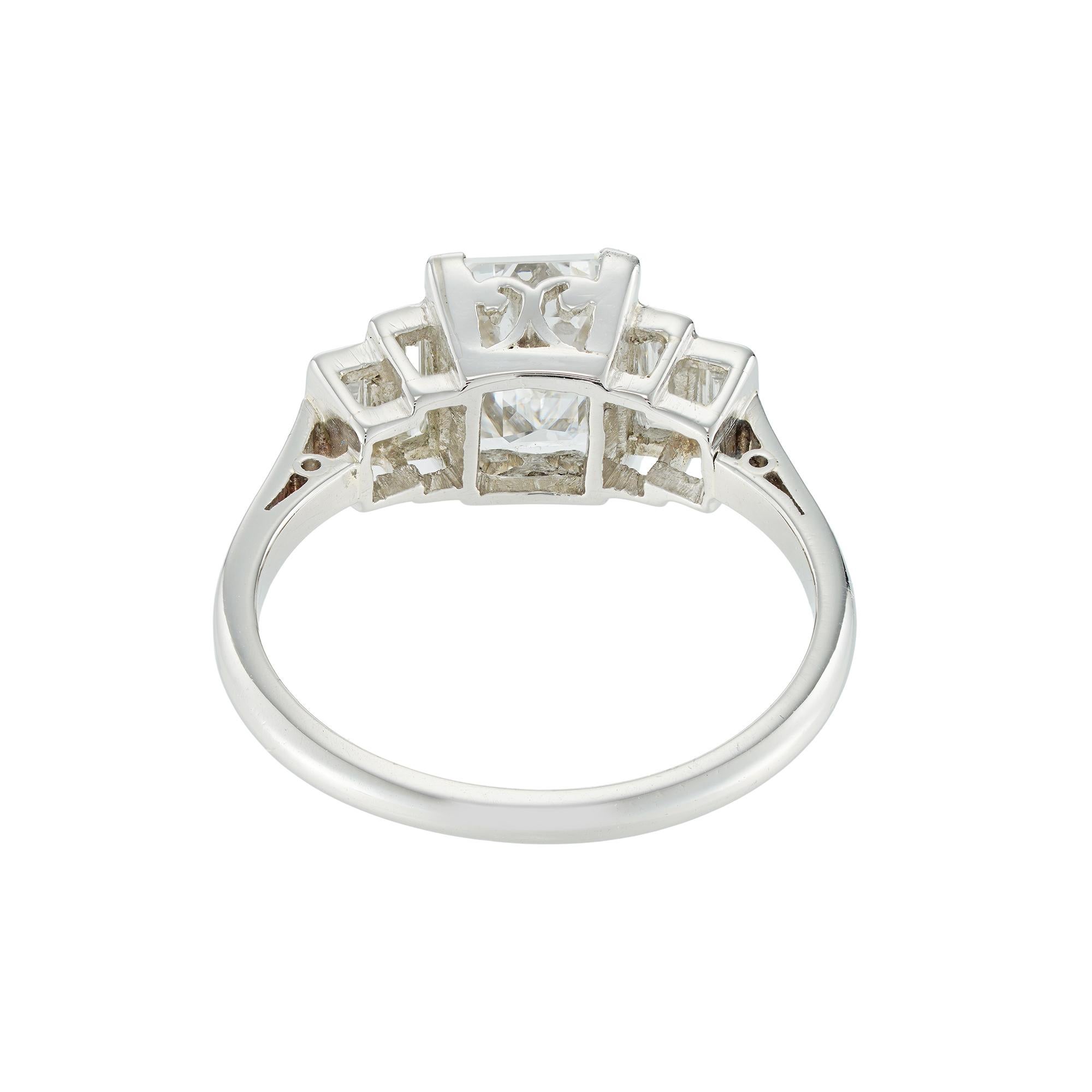 A vintage emerald-cut diamond ring, the emerald cut diamond weighing 1.79 carat, accompanied by DeBeers Report stating to be of D colour and VS1 clarity, four corner claw-set with two graduating in size baguette-cut diamonds on each shoulder, the
