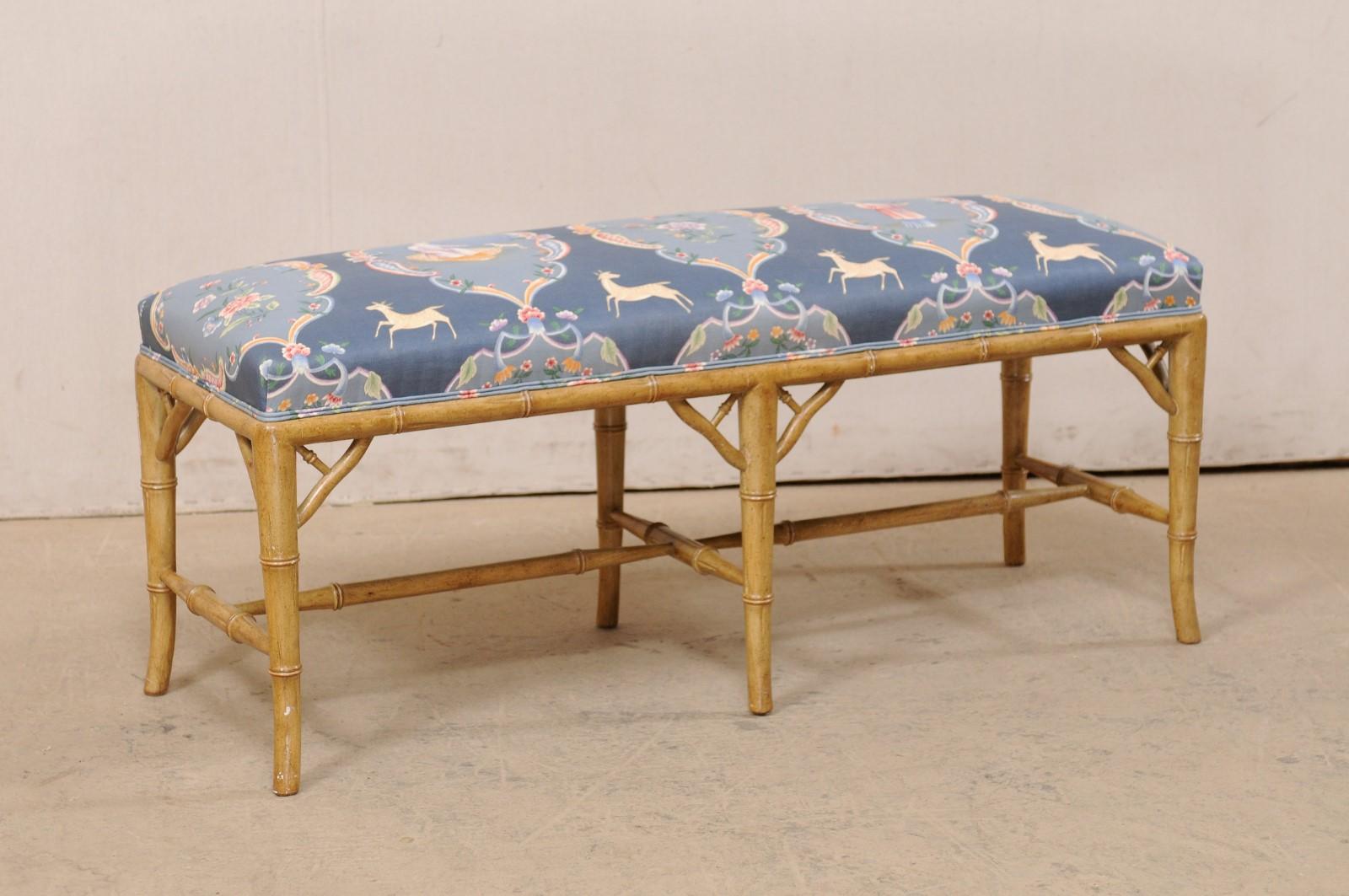 A vintage American faux-bamboo wooden bench with upholstered seat. This cute little bench is approximately 3.5 foot long, and has a wood frame, which has been carved to mimic the design of bamboo. The faux bamboo lines the bottom seat rail, which is