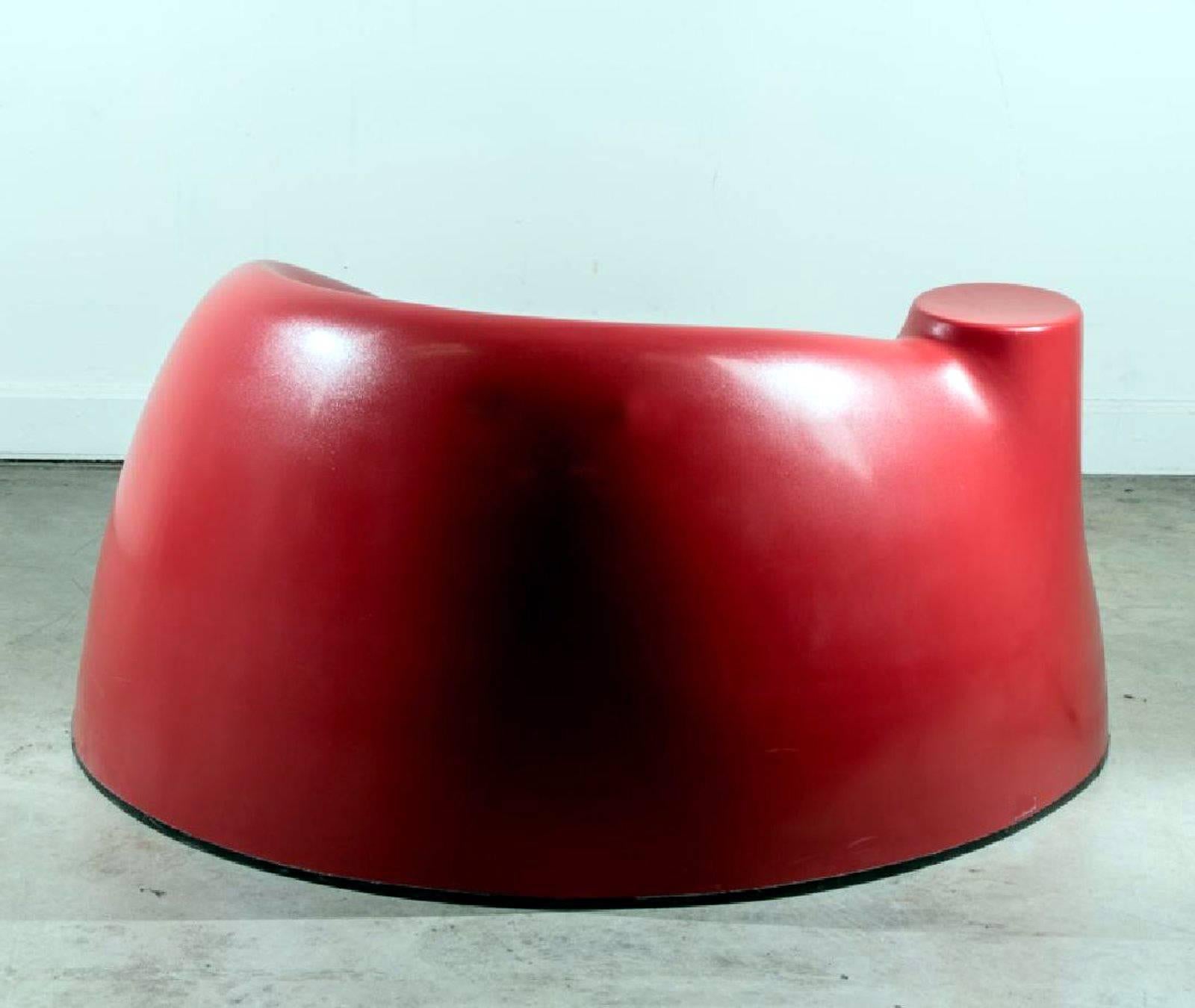 A vintage lounge chair circa 1970s. In dark red color with a cup holder platform and original rubber foot ring. The chair is a playful design after the castle chair, one of the iconic pieces in Wendell Castle's versatile repertoire that uses the