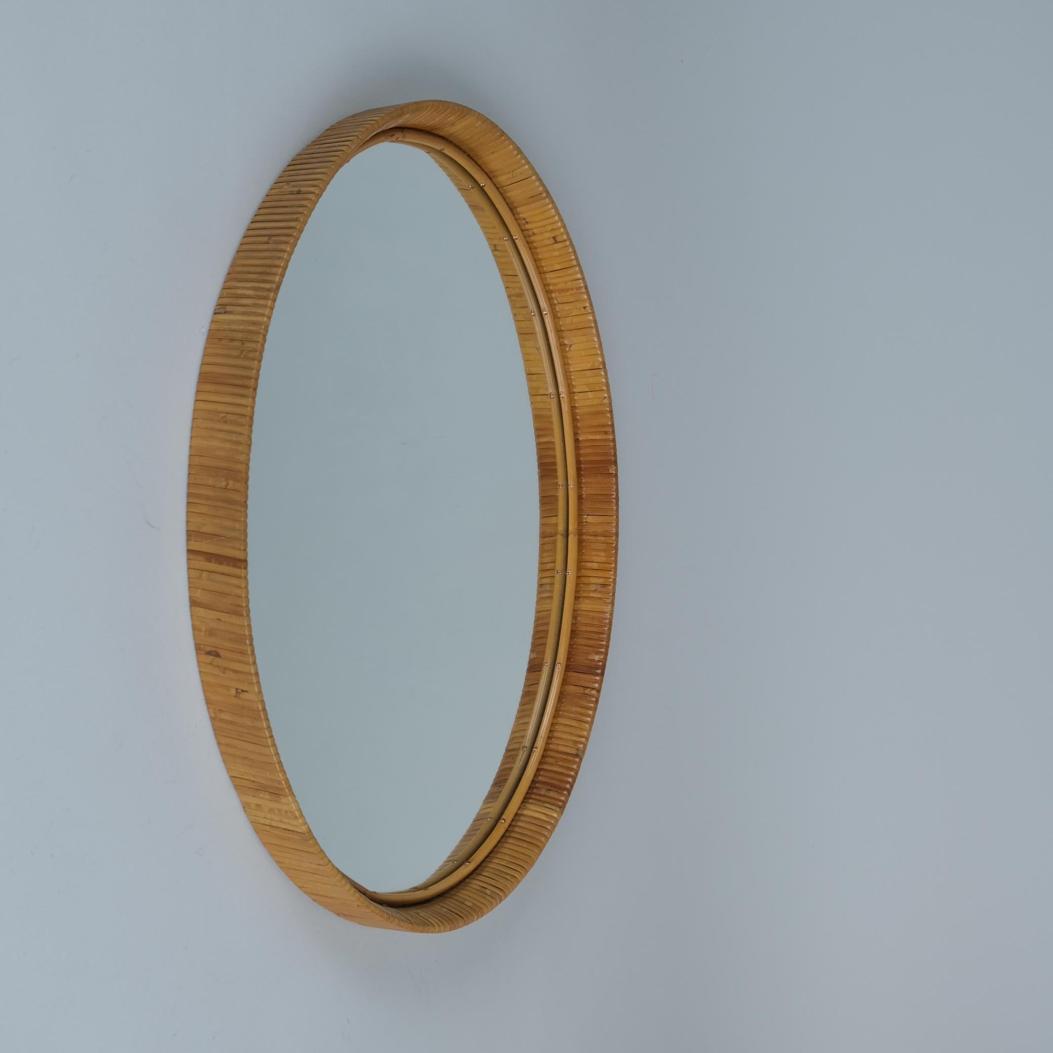Un bellissimo specchio da parete con una splendida patina vintage sulla cornice in rattan e sulla superficie dello specchio. Questo pezzo risale agli anni '50-'60 ed è in condizioni assolutamente originali. Poiché non è timbrata, è quasi impossibile