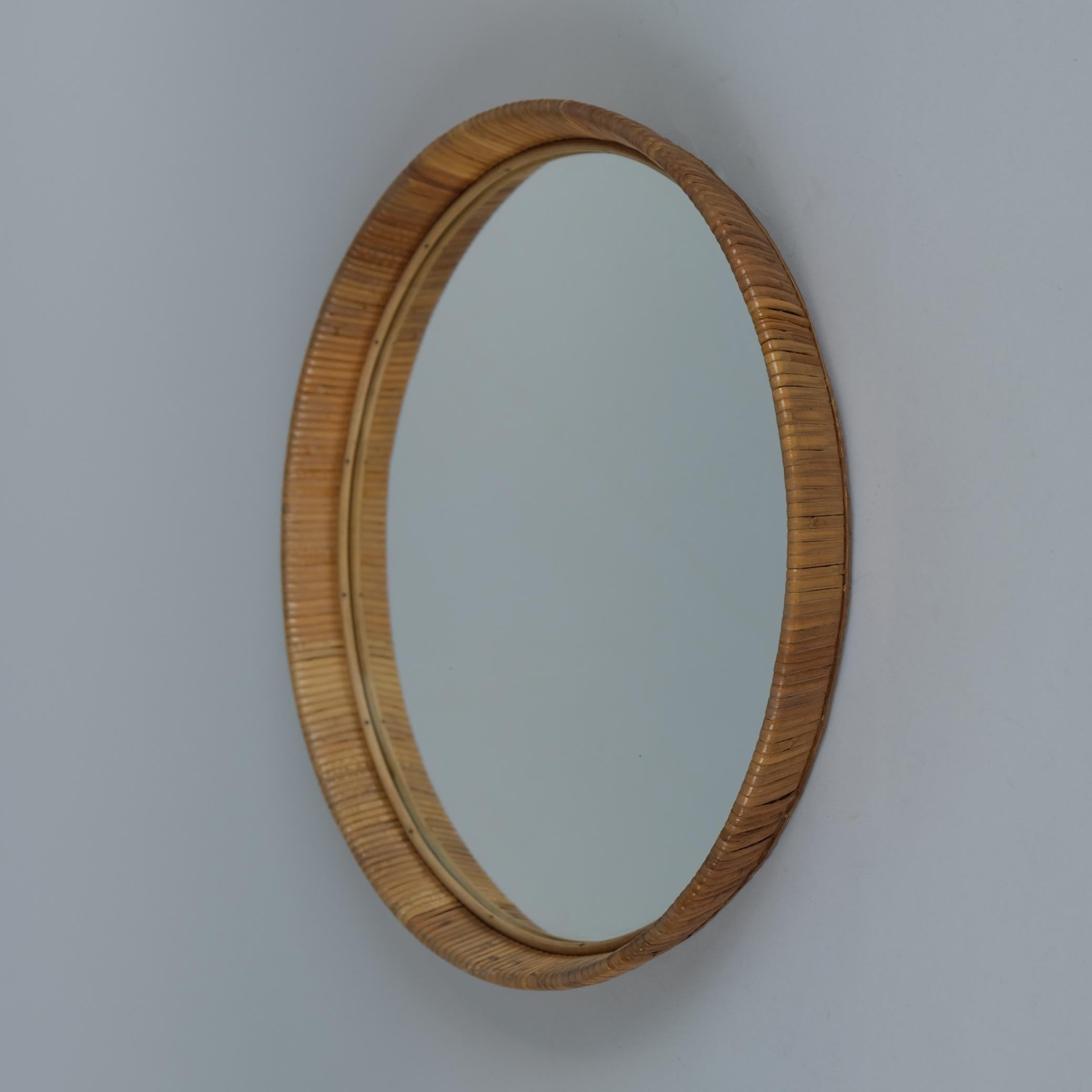 Un bellissimo specchio da parete con una splendida patina vintage sulla cornice in rattan e sulla superficie dello specchio. Questo pezzo risale agli anni '50-'60 ed è assolutamente in condizioni originali. Poiché non è timbrata, è quasi impossibile