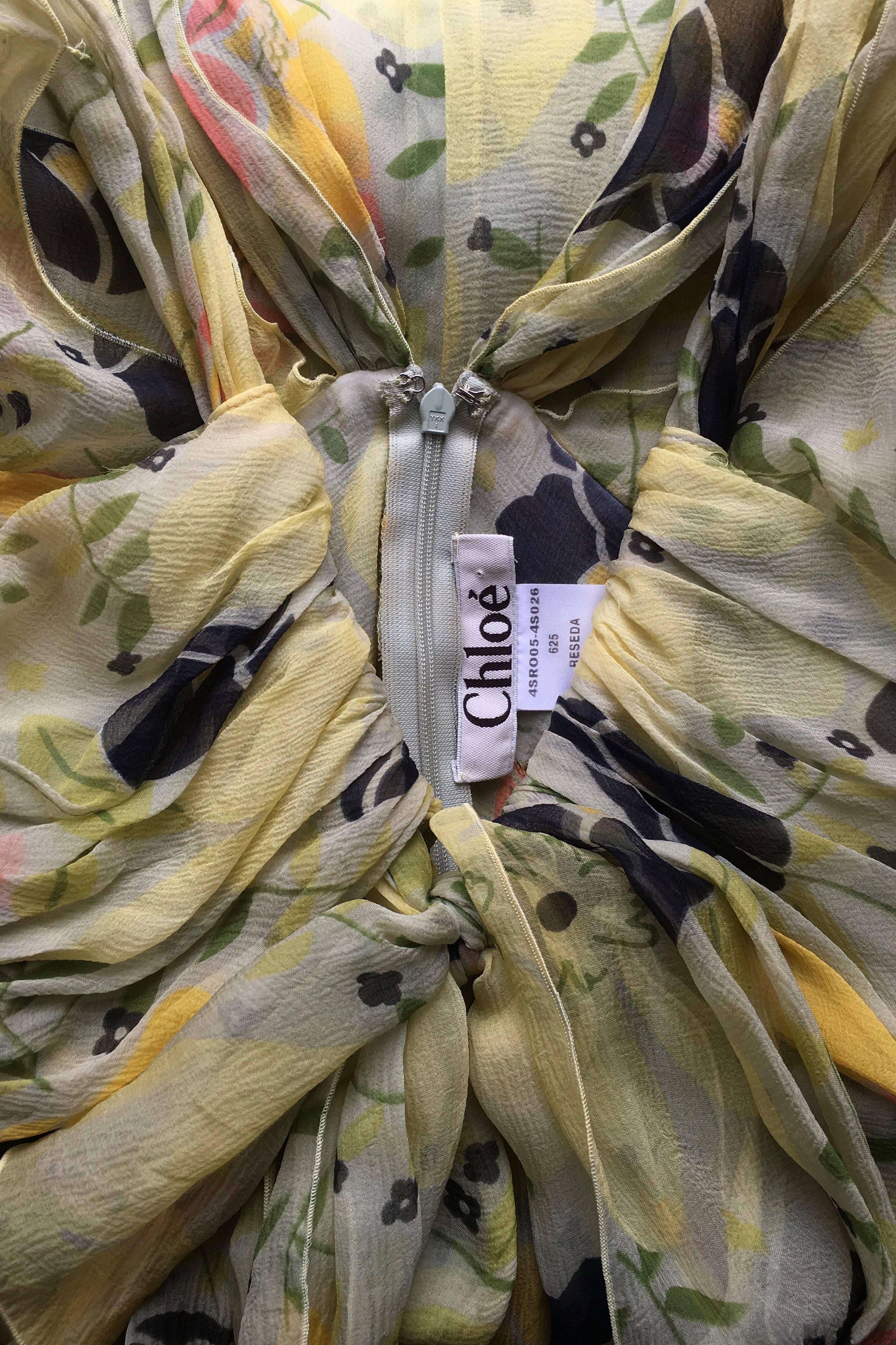 A fabulous Chloé silk chiffon dress in bright yellow with a gorgeous floral print. Demure ruffles and ruching at the neck compliment the multilayered skirt. 

The size of the skirt corresponds to a modern size extra small, but please see the