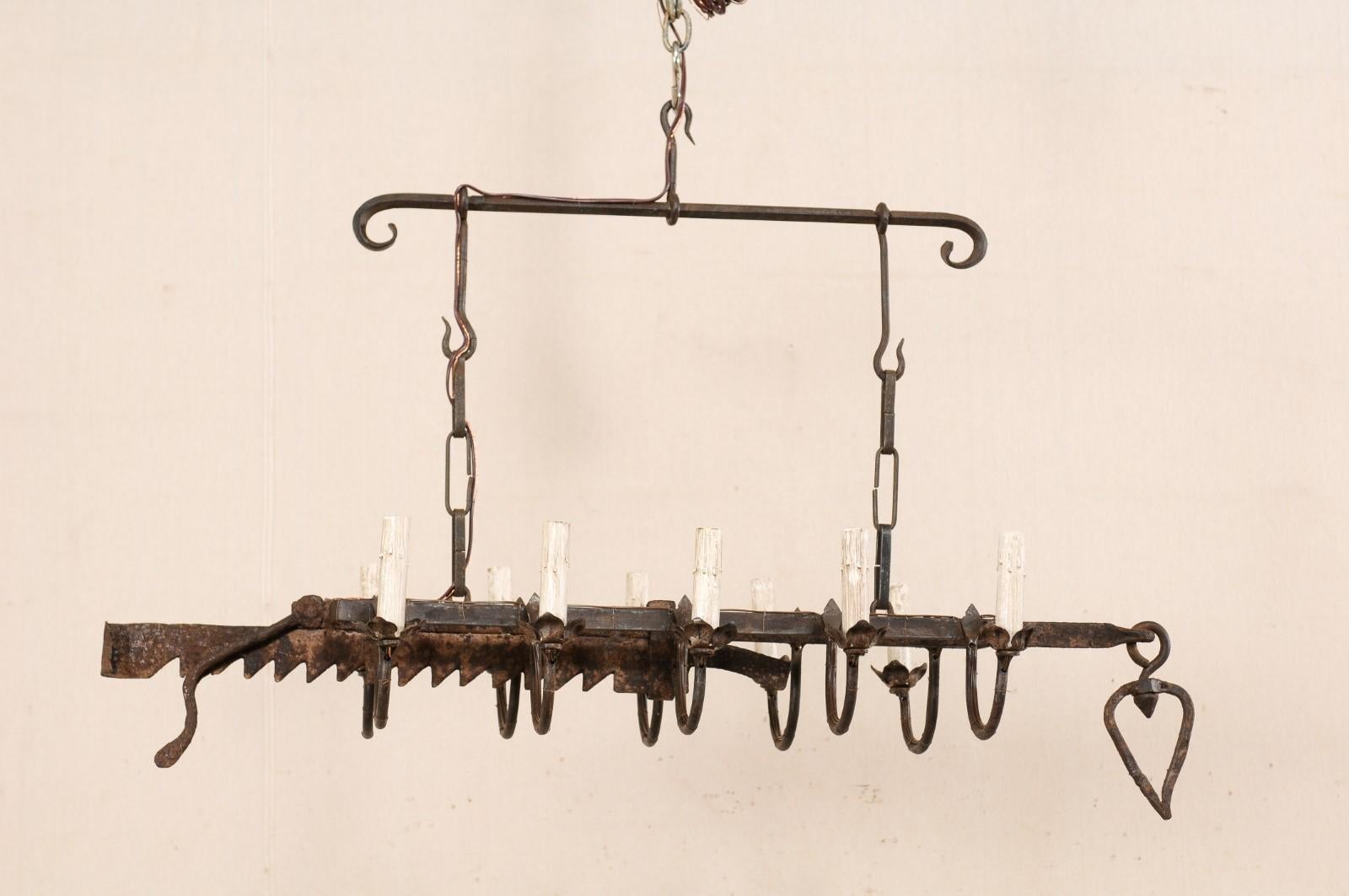 A vintage French ten-light forged-iron chandelier made from a 19th century spit-jack. This French hanging light-fixture, from the mid-20th century, has been fashioned from an earlier 19th century spit-jack, which was once used as a type of