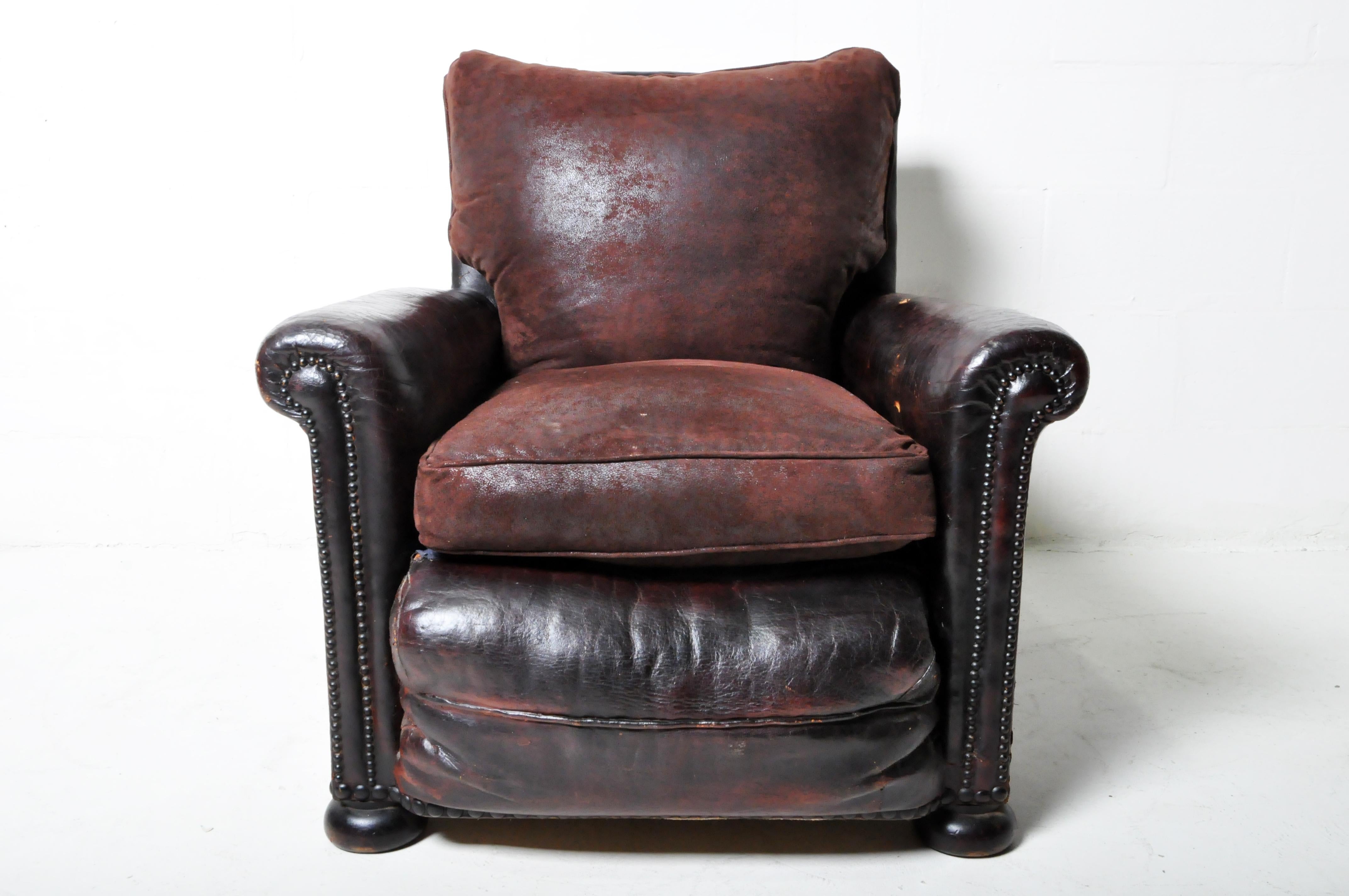 A generously-proportioned French leather club chair with bun feet and dark sheepskin upholstery. The modern seat and back cushions have been artfully fabricated to match the original design and color. Restoration to springs and some repairs to