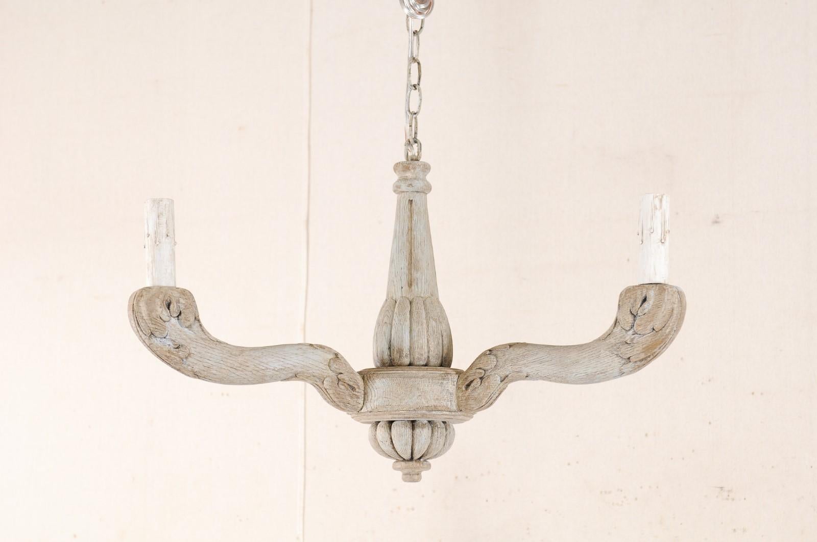 A French carved and painted wood, three-light chandelier from the mid-20th century. This vintage chandelier from France features a carved central column with rounded gallery which supports three arms carved with leaves. Each arm terminates into a