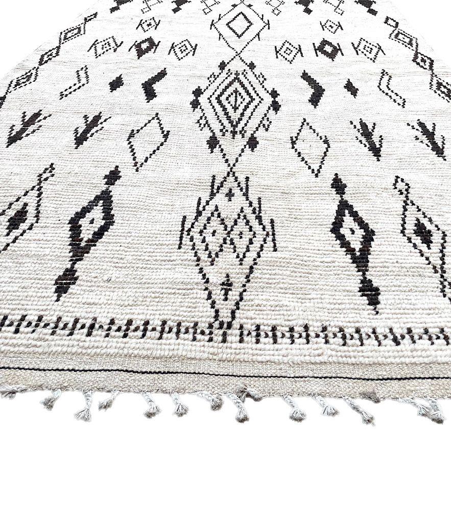 A vintage handwoven Moroccan berber rug with tribal diamond and line pattern, in black and white handwoven wool by the Beni Ouarian tribe. A wonderful geometric design with woven wool tassels on each end.
