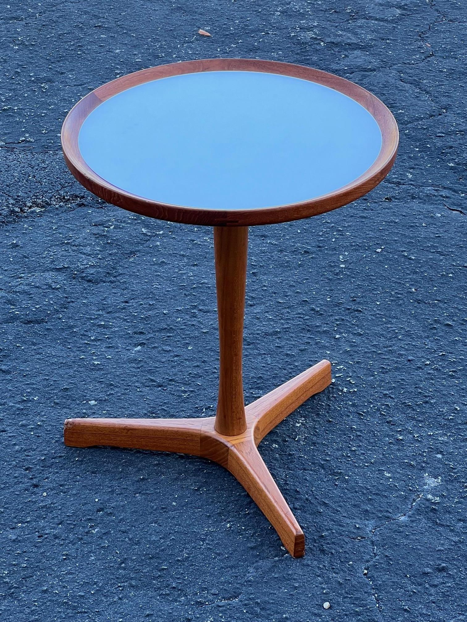 A classic Danish side table with three legs by Hans Andersen. Round top in white mica, teak wood, finger joined on top. Nice patina and very good / excellent original condition. 