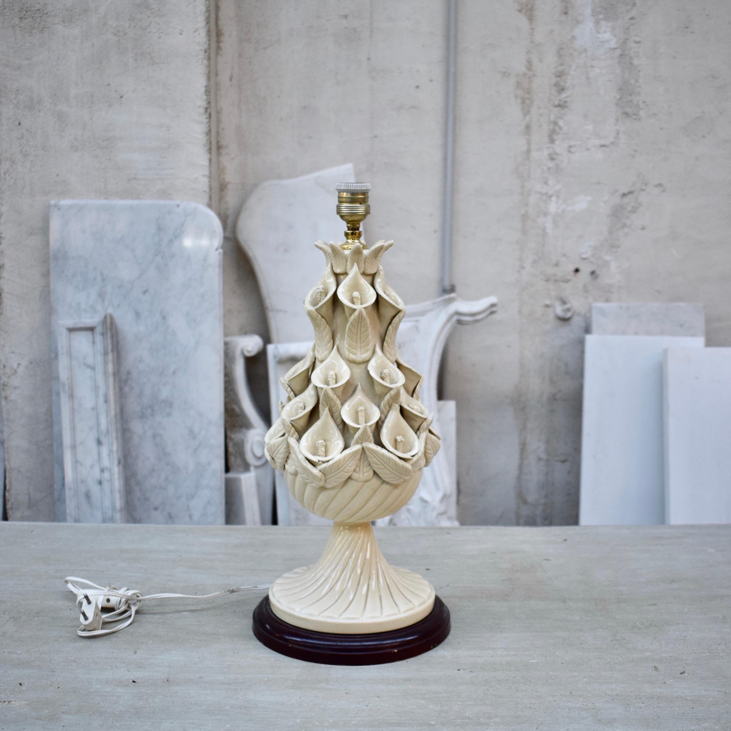 This vintage Manises ceramic table lamp by Ceramica Bondie was made in Spain near Valencia during the 1960s. It is glazed in a wonderful ivory/white ceramic color with handmade floral motifs adorning the sides of the lamp. It stands on a wooden