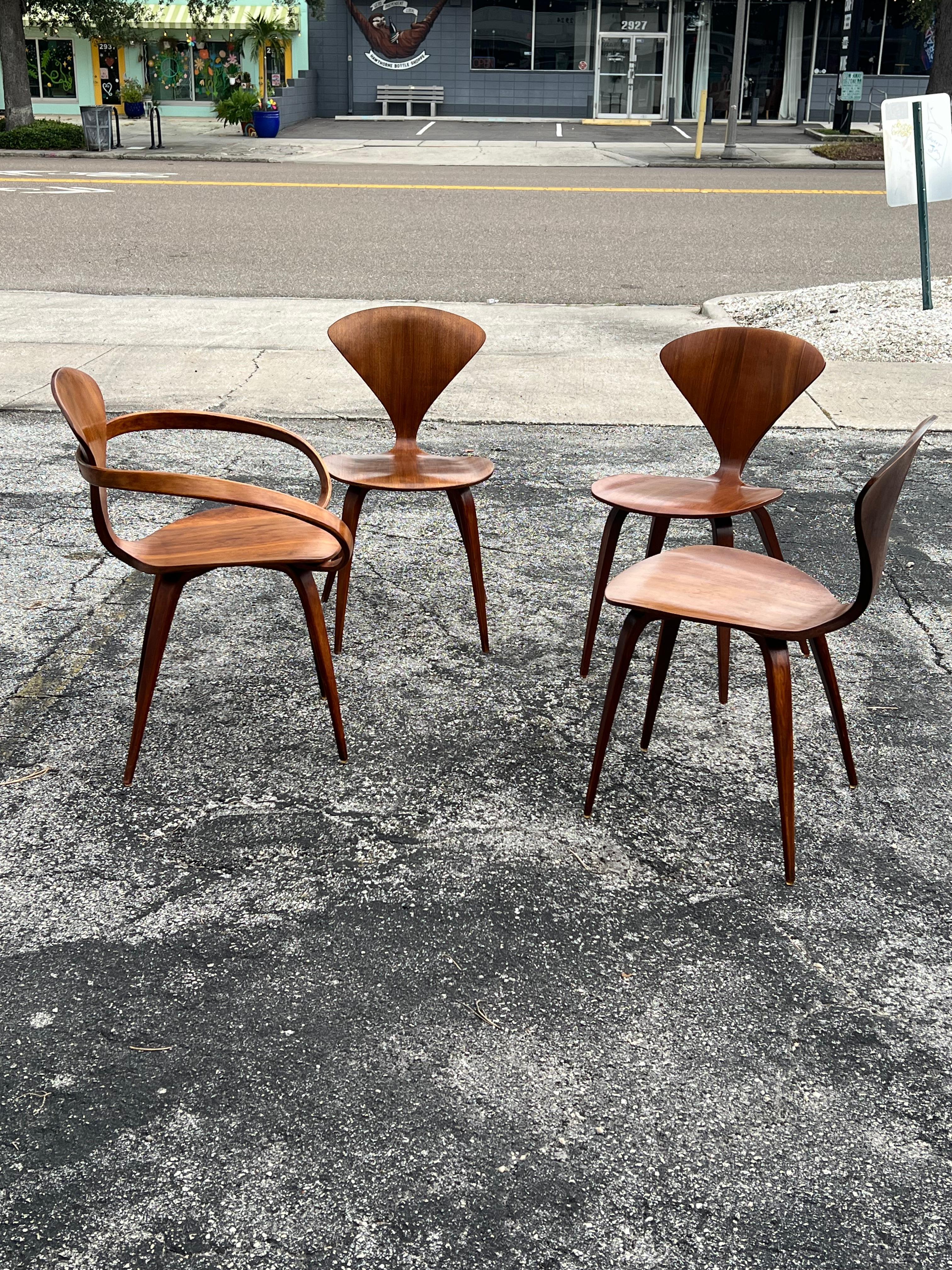 Una silla Norman Cherner vintage de 1ª edición con brazos y tres sillas sin brazos.  Nogal con una pátina agradable y rica. Dos sillas firmadas con etiquetas. Original de hacia 1950.