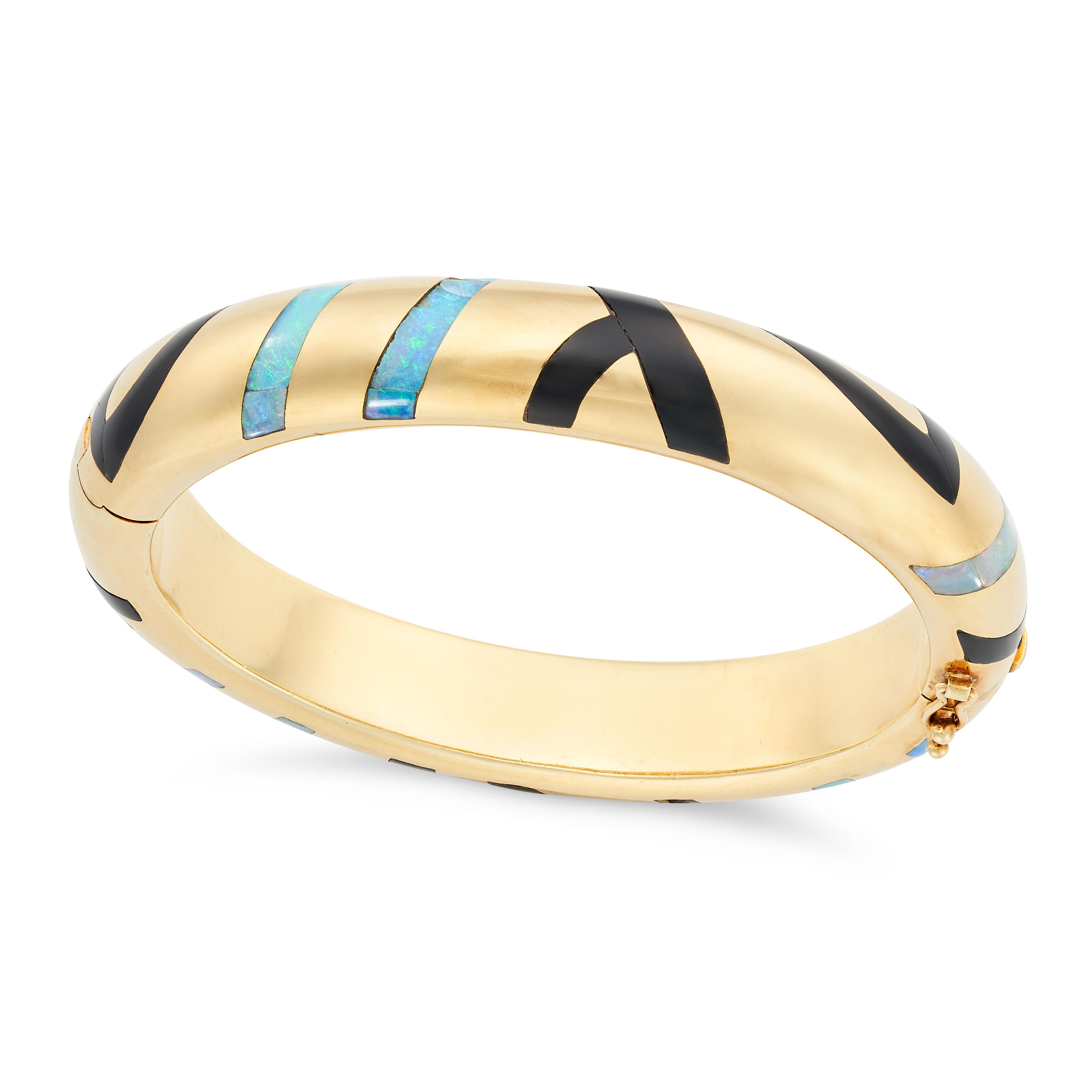 Este maravilloso brazalete es un ejemplo perfecto del diseño de los años 80, con paneles ondulados y sin juntas de ónice y vibrante ópalo incrustados en oro amarillo liso de 18 quilates, un complemento perfecto para cualquier colección de joyas. 