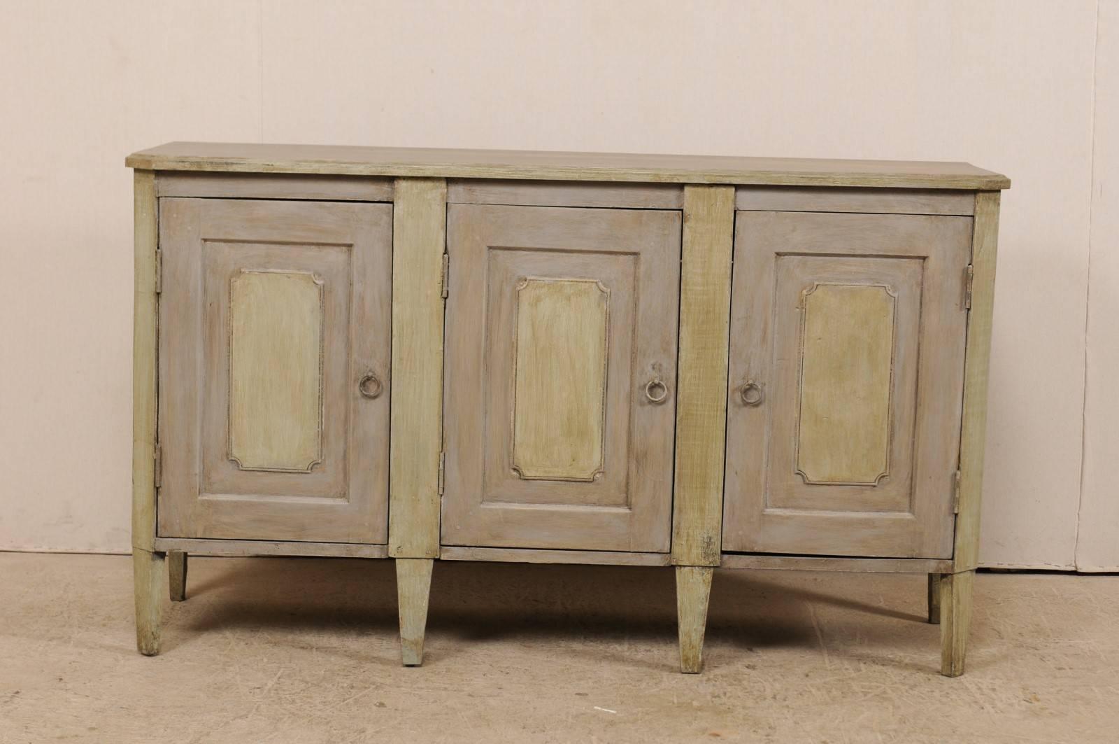 A vintage American painted wood buffet sideboard cabinet. This American cabinet is simplistically designed with nice, clean lines. It features three recessed paneled doors with accentuated centers, set within a case that has canted side posts, and a