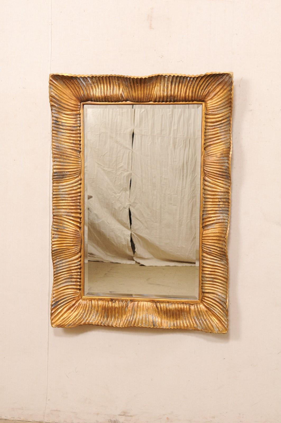 A vintage Hollywood Regency style mirror. This American-made Regency Moderne style mirror, constructed of composite resin with a copper/bronze finish, has a rectangular-shape with a delightful inwardly curling scalloped surround of undulating ridged