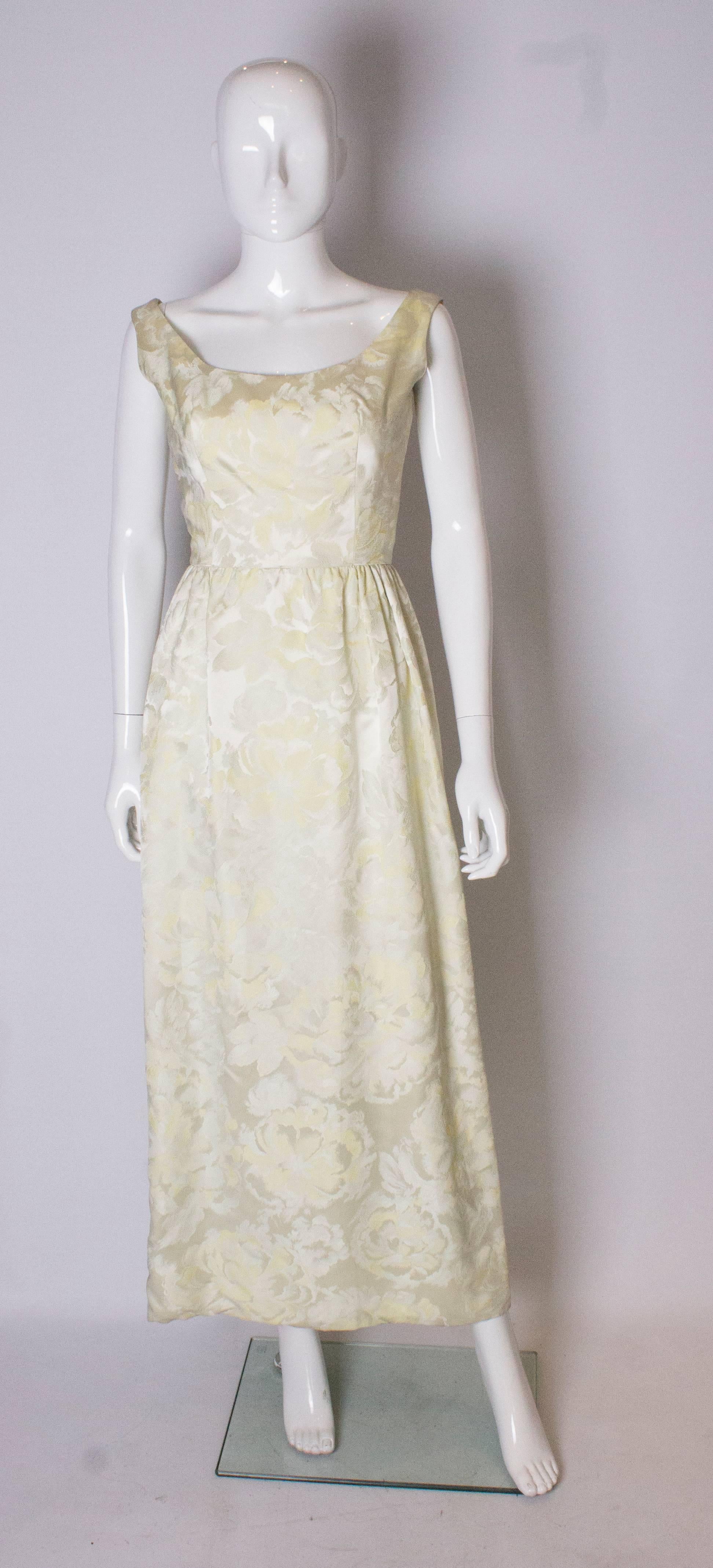 A stunning vintage gown by US designer Sarmi, ideal for Spring/Summer. The gown has a deep neckline at the front  and back, and is in a pale yellow , floral print brocade fabric. The dress is fully lined and has a central back zip.