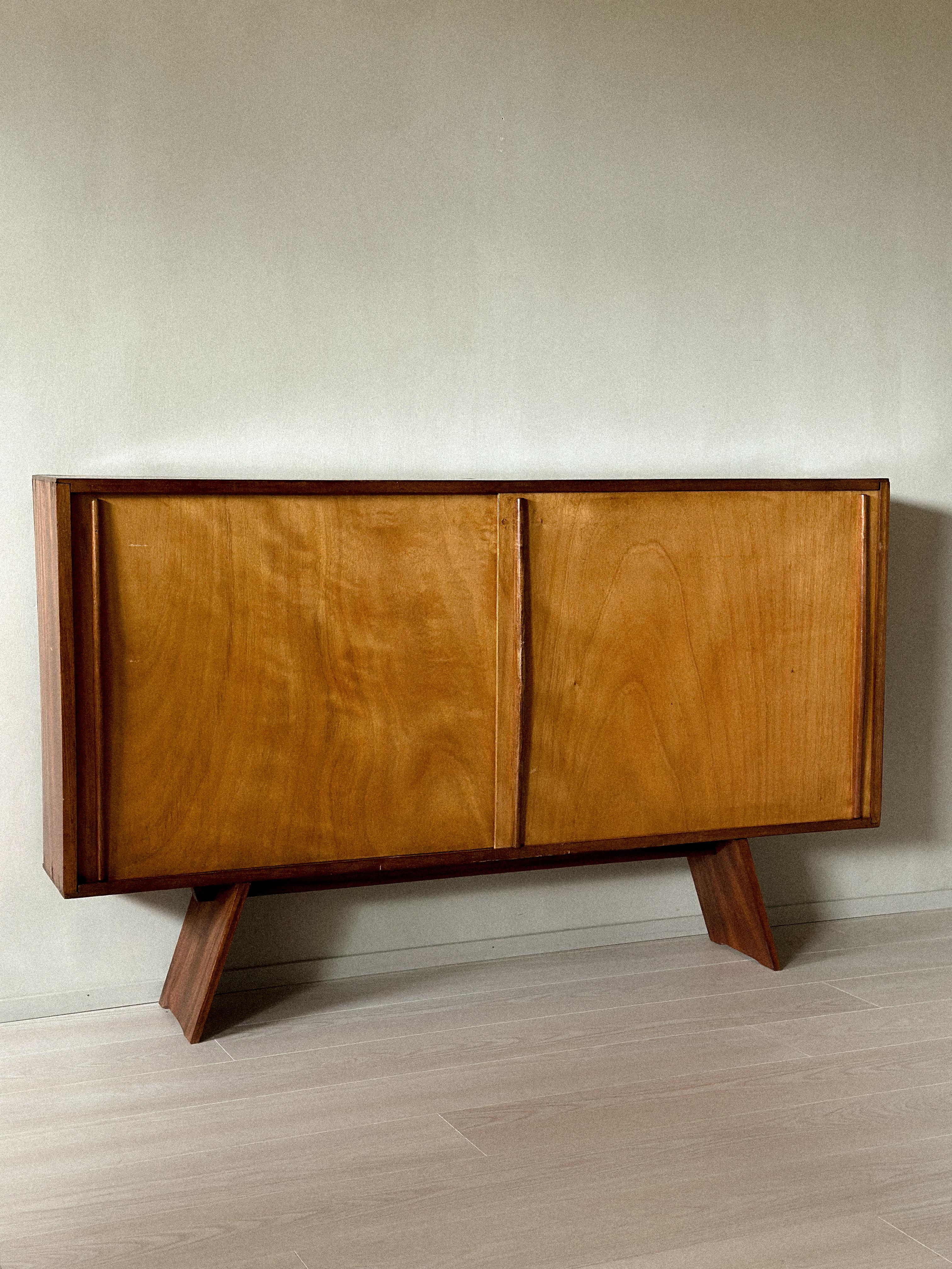 Vintage sideboard in the style of Charlotte Perriand, France, circa 1950s. Functional design with sliding doors and open storage. Wear consistent with age and use, including marks, scratches, and wear to the veneer.
