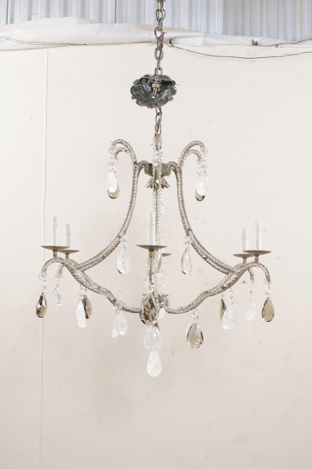 An American six-light chandelier adorn in rock and smoky crystals. This vintage chandelier features delicately scrolled body adorn with various smoke and rock crystals, iron armature lined with glass beading along it's structure, a waterfall