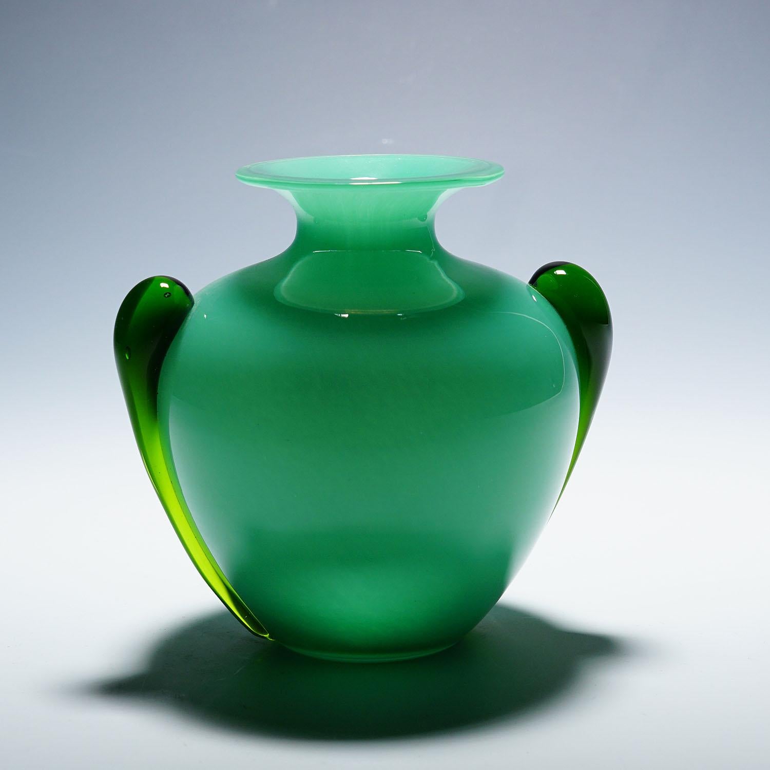 Vase Vintage en verre d'art Soffiato Murano ca. 1950s
Article e7130
Un superbe vase en verre d'art de Murano. Verre opaque vert fin avec recouvrement en verre clair et poignées en forme de goutte d'eau. Producteur inconnu, très probablement Murano