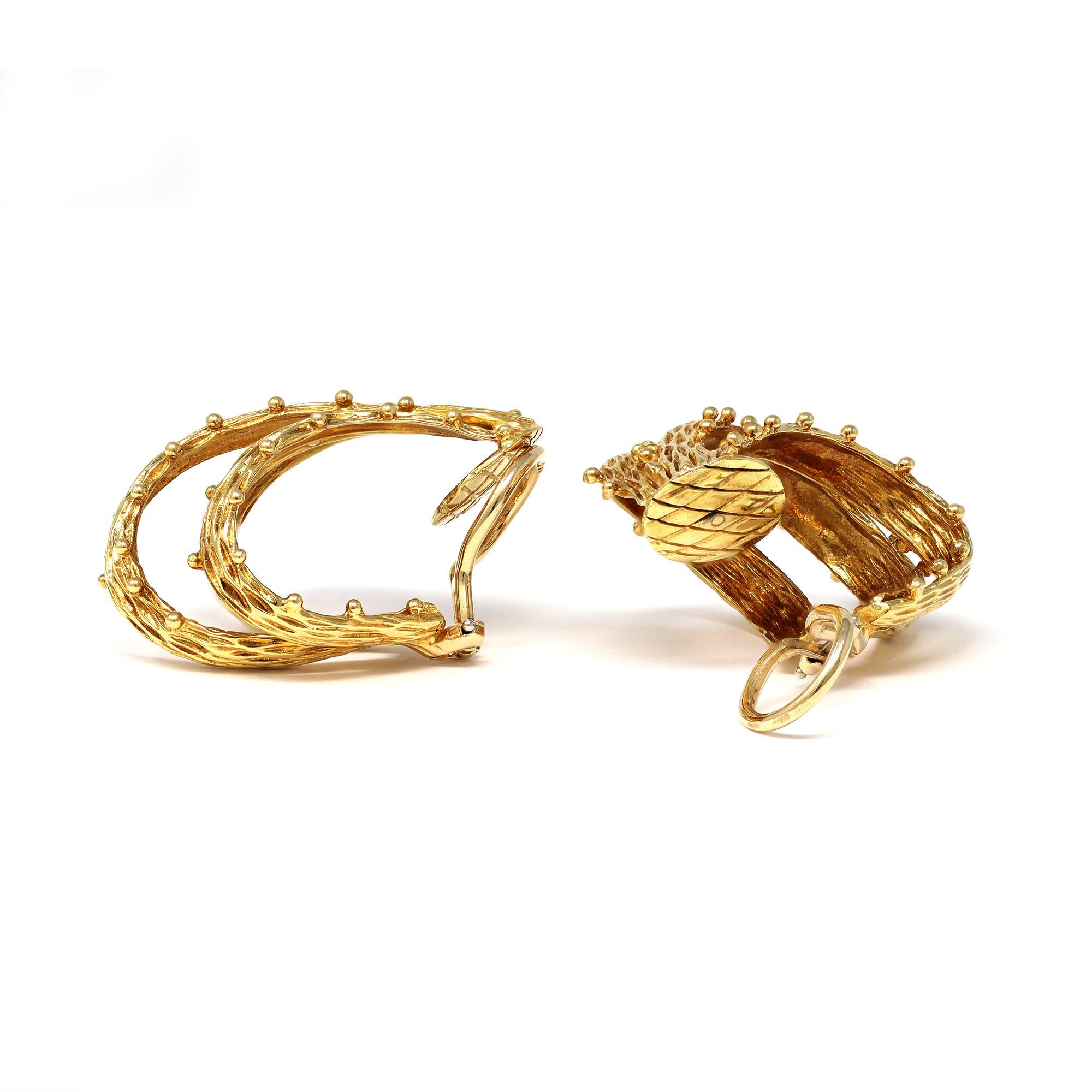 A vintage triple branch hoop clip on earrings circa 1960 featuring an intricate gold work that évoques wood texture. The earrings are particularly flattering because of the scale and the rich yellow gold color. They measure 1.32”long and 1.09” wide.