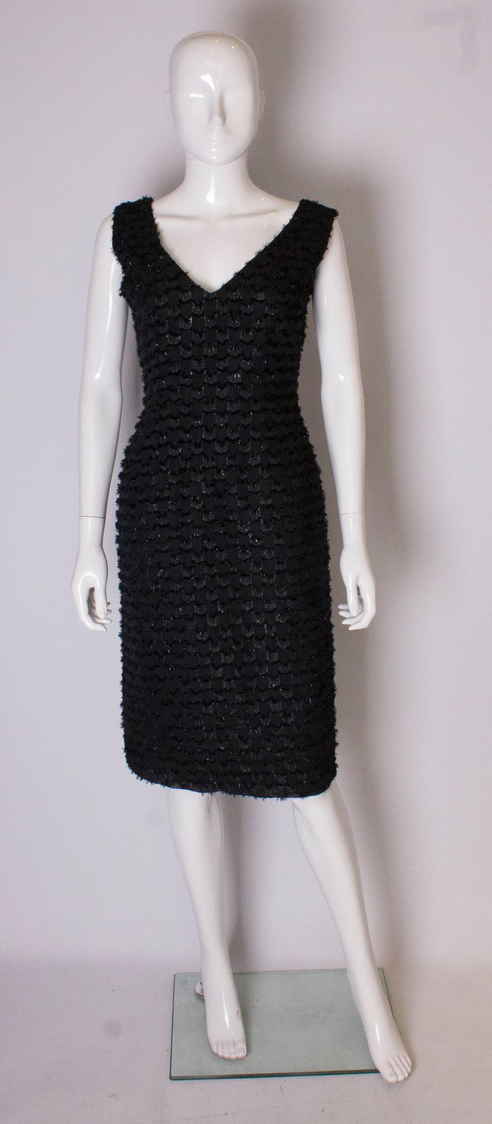 Un piccolo abito nero vintage chic di Tussi of Australia. L'abito ha uno scollo a V e una scollatura sulla schiena,  e presenta un dettaglio di ciuffi sul corpo. È completamente foderato e ha una zip centrale sul retro.