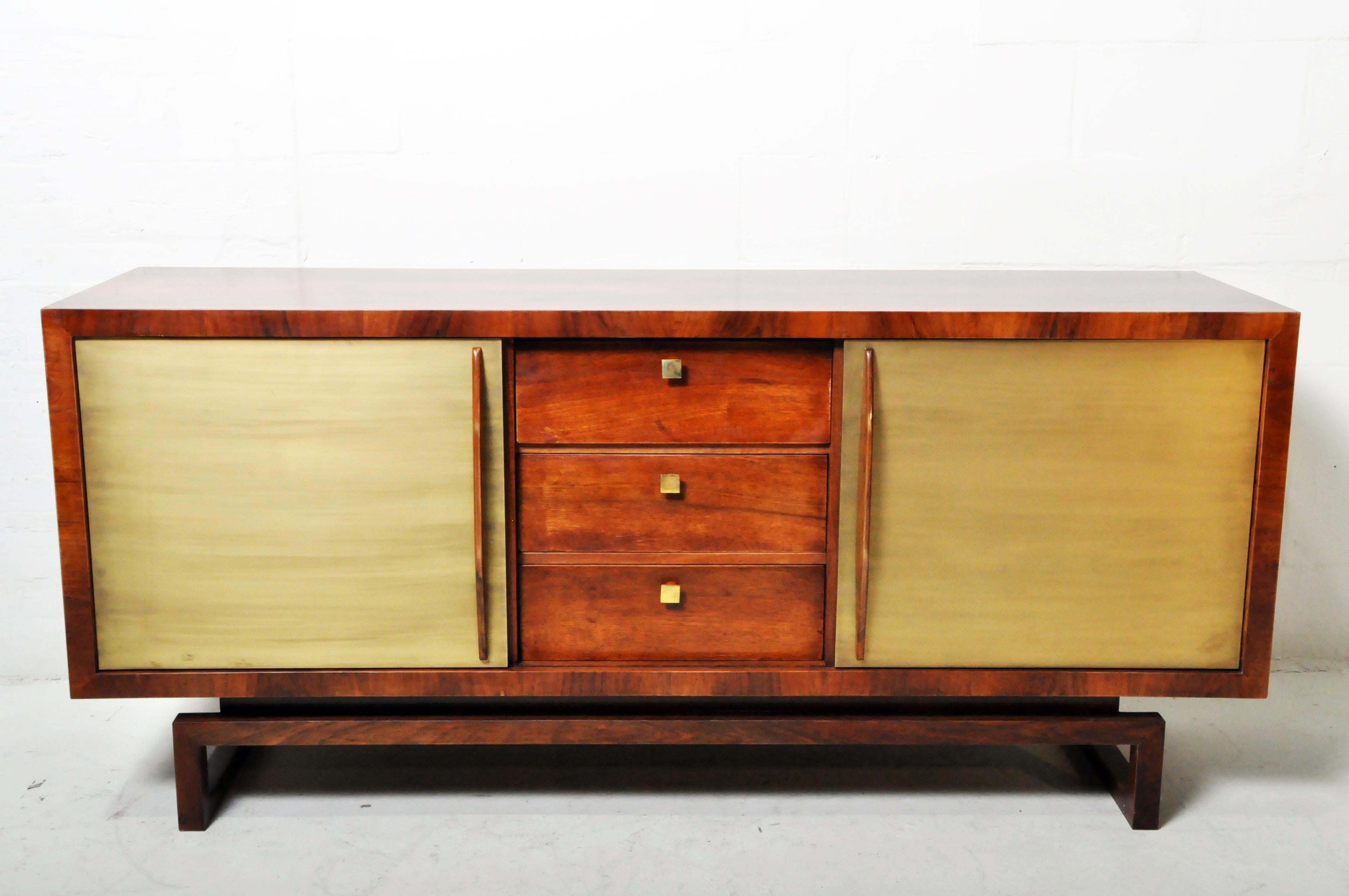 A Hungarian Mid-Century Modern sideboard in walnut veneer and brass-sheathed doors. Hungarian mid-Century Furniture rarely utilized exotic imported hardwoods, such as teak, and substituted native walnut wood instead. This sideboard features a richly