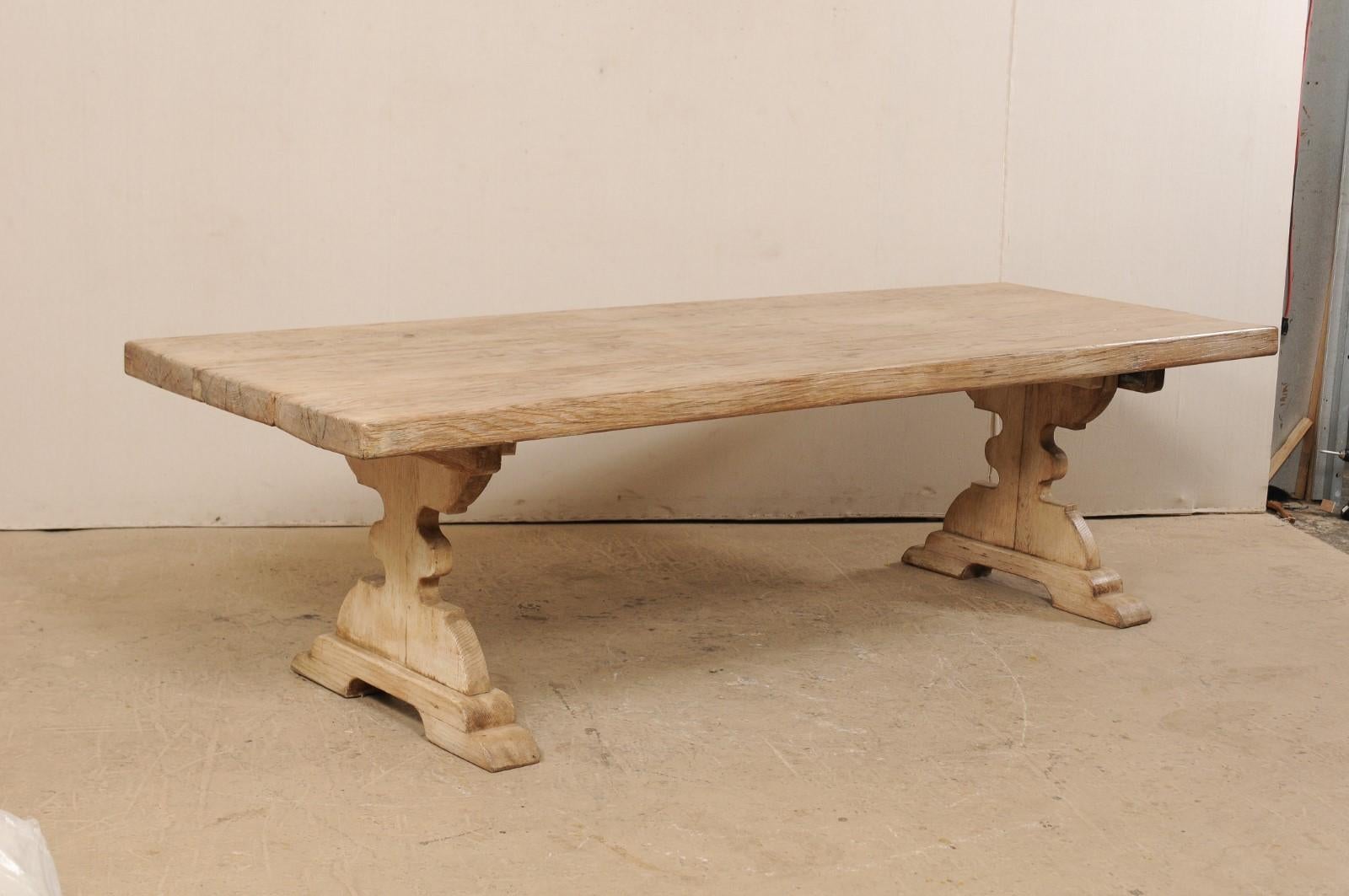 A vintage American carved wood trestle table. This rectangular-shaped dining table, just over 9 feet in length, features a 3