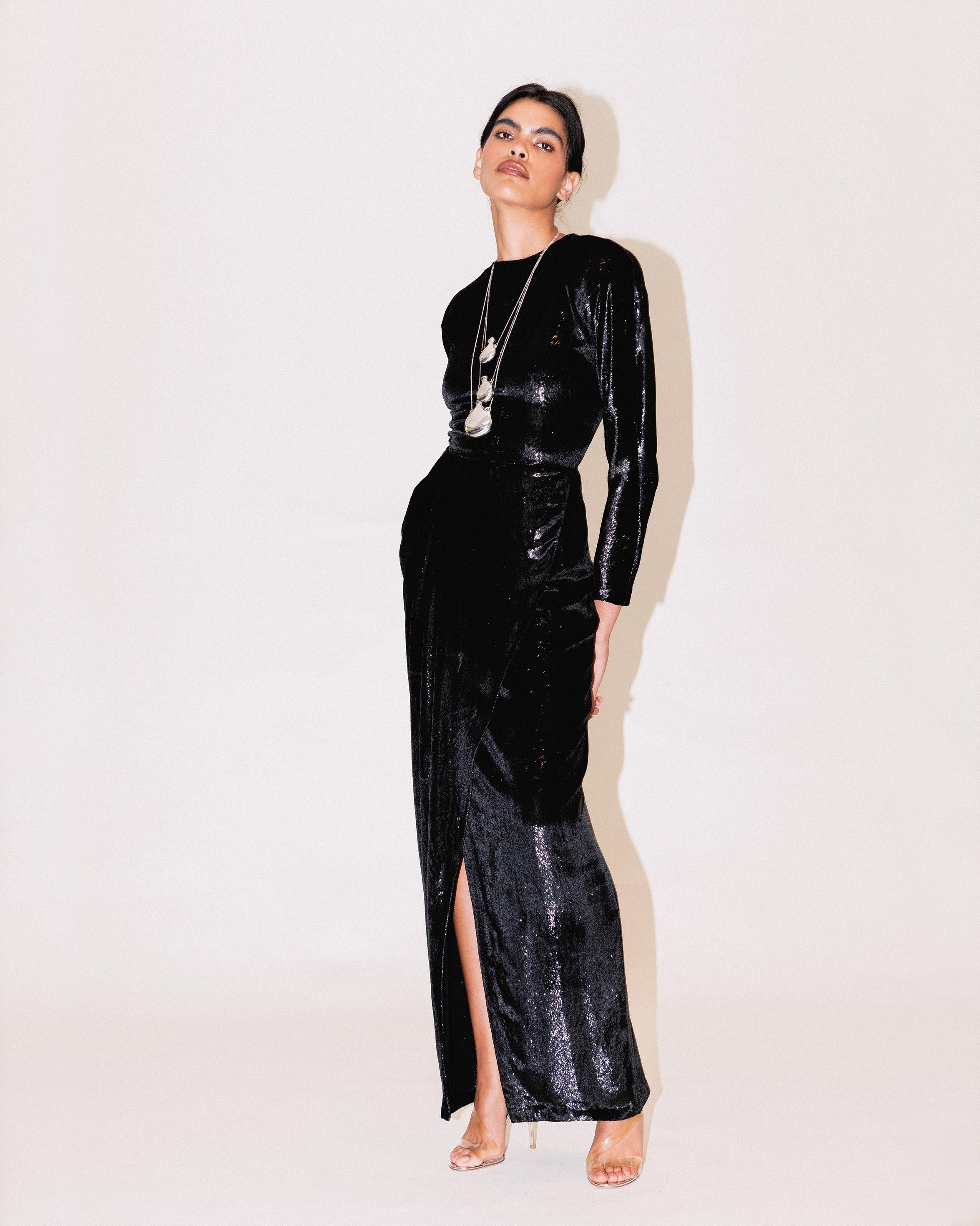 A/W 1989 Geoffrey Beene black lamé long sleeve gown. Silk and tinsel blend metallic lamé velvet gown with long sleeves and built-in shoulder pads (removable as desired). Fitted waist and open asymmetrical drape wrap front with side slit. Concealed