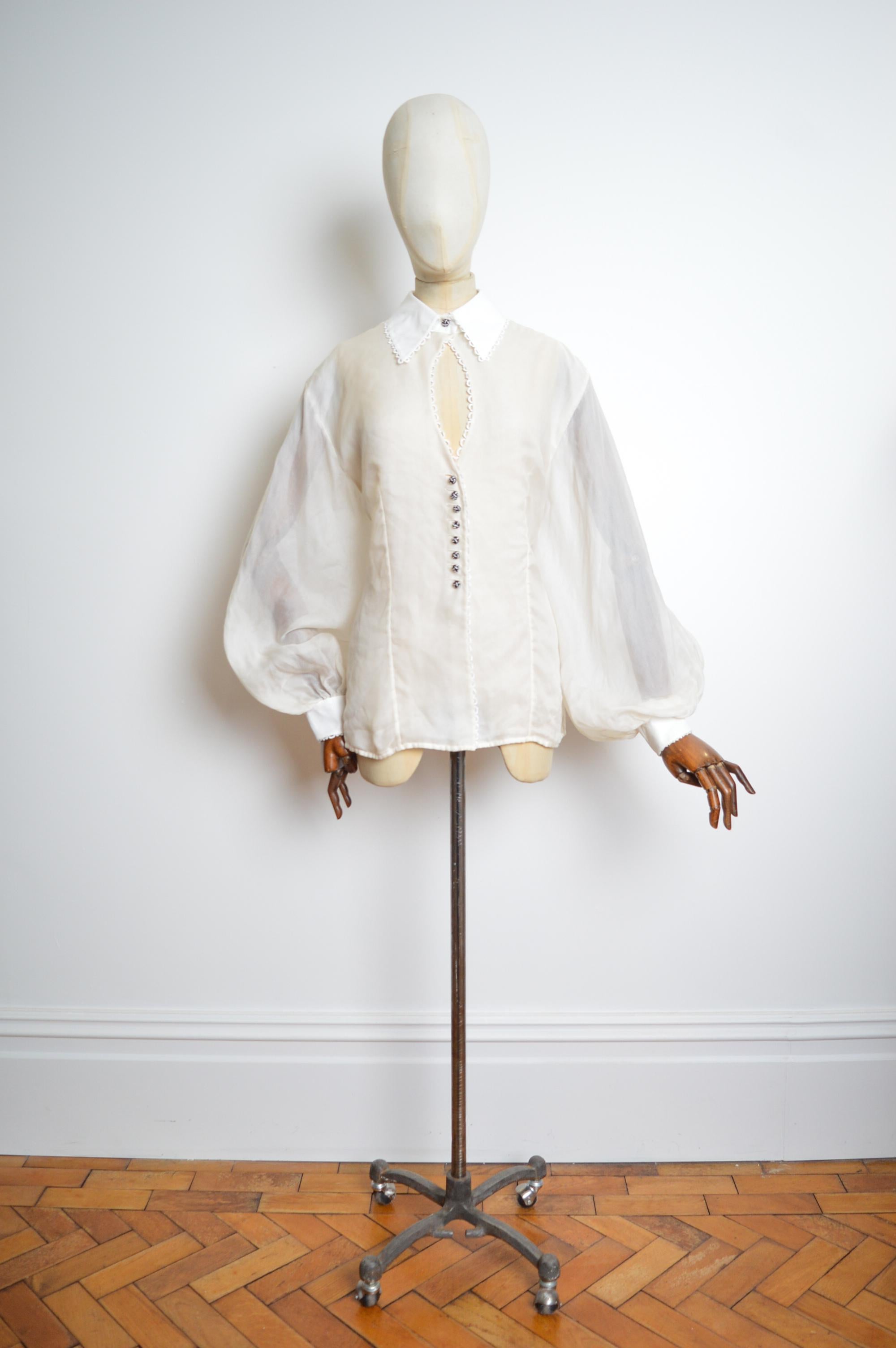 Superb Autumn / Winter 1995 - 1996 CHRISTIAN DIOR by Gianfranco Ferré !
This Balloon sleeved runway Blouse is crafted from a Sheer White raw silk blended material with contrast cotton cuffs and collar, broderie anglaise detailed trims, cut out 'Key