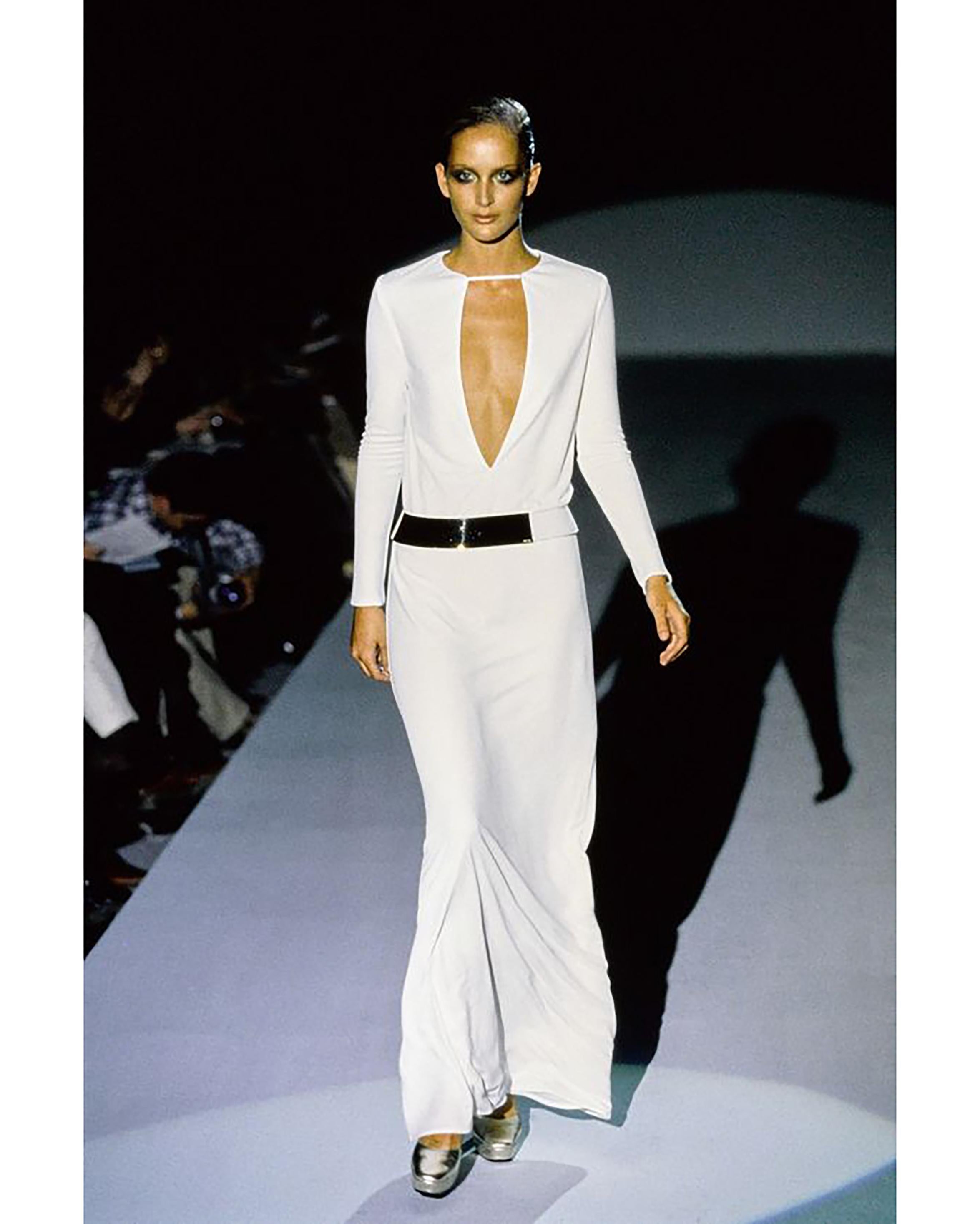 A/W 1996 Gucci by Tom Ford white jersey long sleeve gown. Chic soft silk jersey white plunged neckline long sleeve maxi dress. Front cutout detail with white and gold stamped removable belt. Concealed snap closure at upper cutout strap, and small