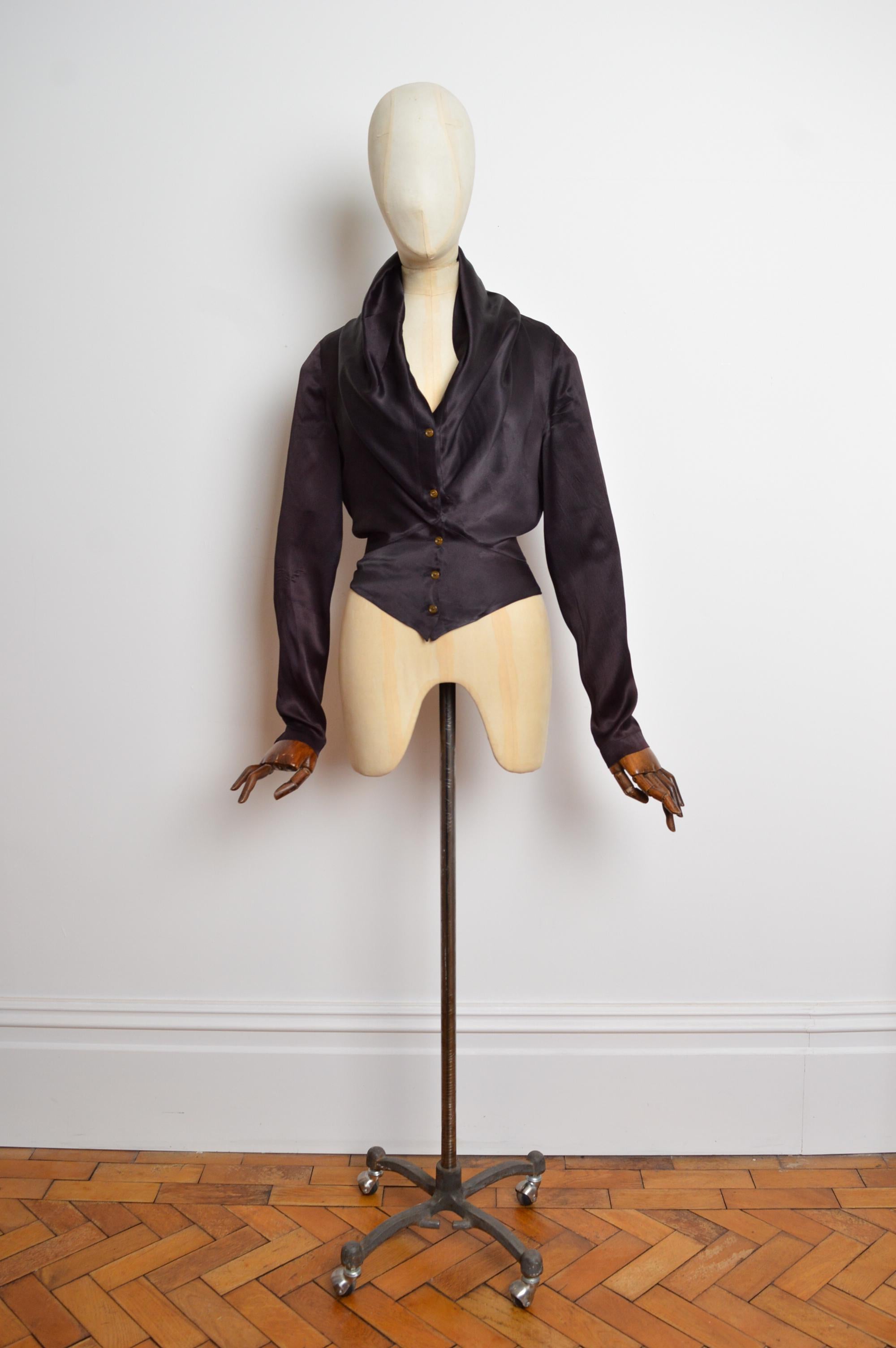 Eine bemerkenswerte Bluse von Vivienne Westwood aus der Herbst/Winter-Kollektion 1996. Sie ist aus wunderschön drapiertem schwarzem Satin gefertigt und mit durchgehenden Knöpfen versehen, die der Trägerin grenzenlose Stylingmöglichkeiten bieten.