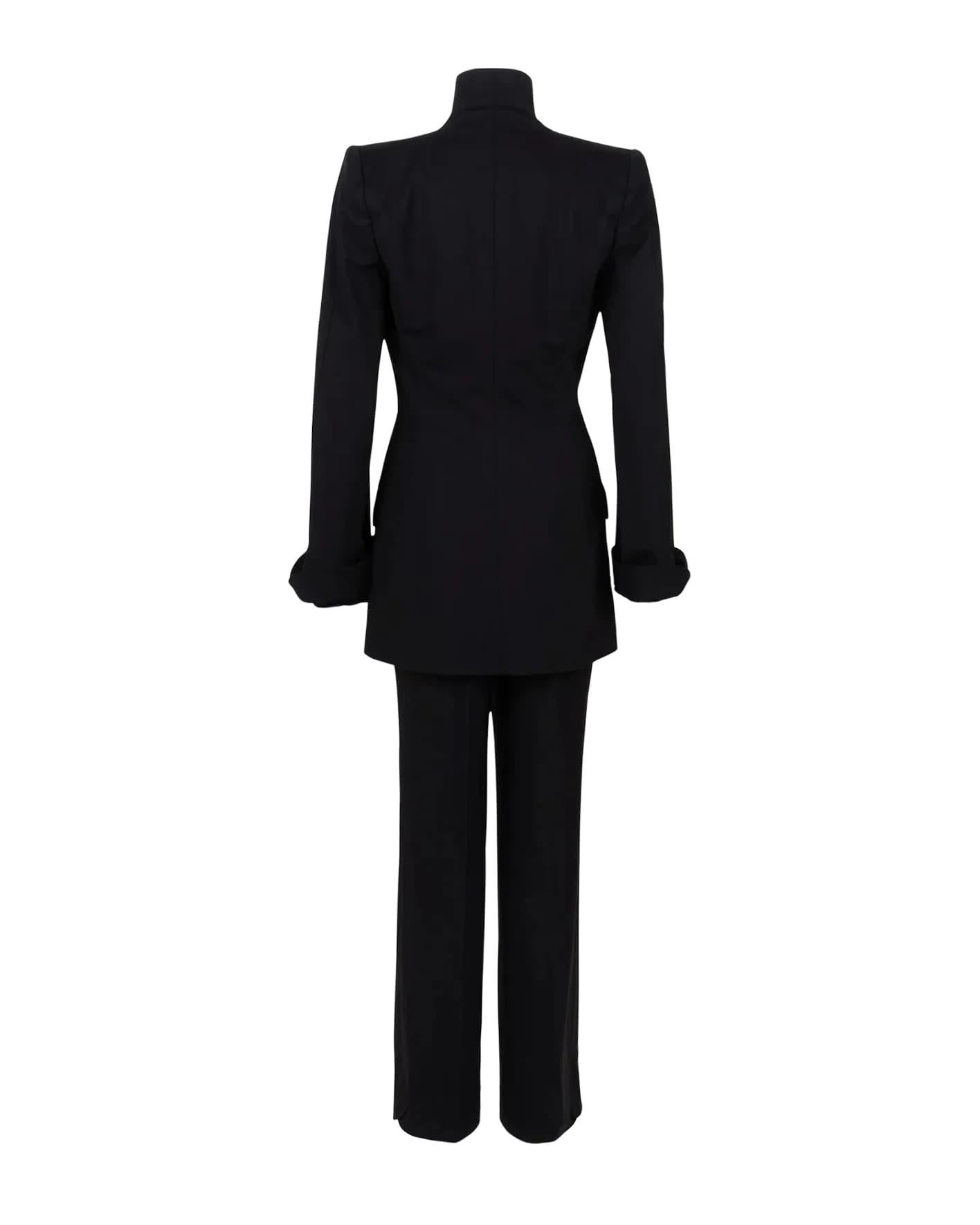 A/W 1997 Givenchy by Alexander McQueen Haute Couture double-breasted pant suit set. Simple, chic black wool suit from McQueen’s first year at Givenchy. Jacket has built up neckline, pockets, flared sleeves, and red rhinestone front closures. Pairs