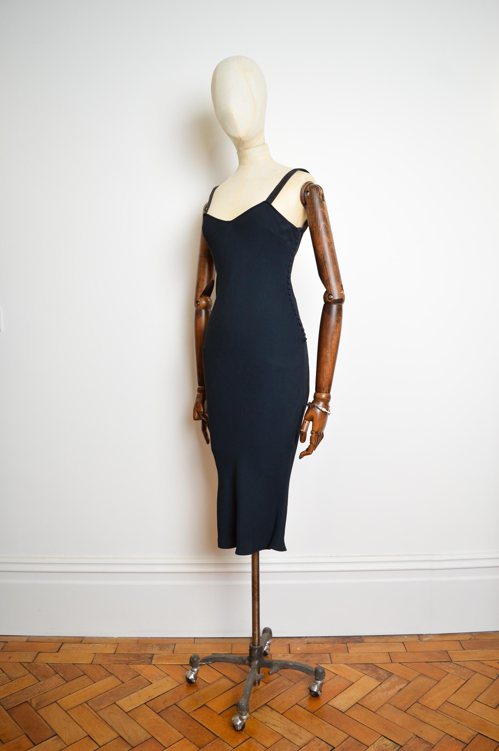 This Rare and Iconic slip dress for Christian Dior's Spring / Summer 2001 Collection designed by John Galliano features a simple bias-cut silhouette, numerous fabric-covered buttons up the side detailing, Goat velvet shoulder straps and a deep