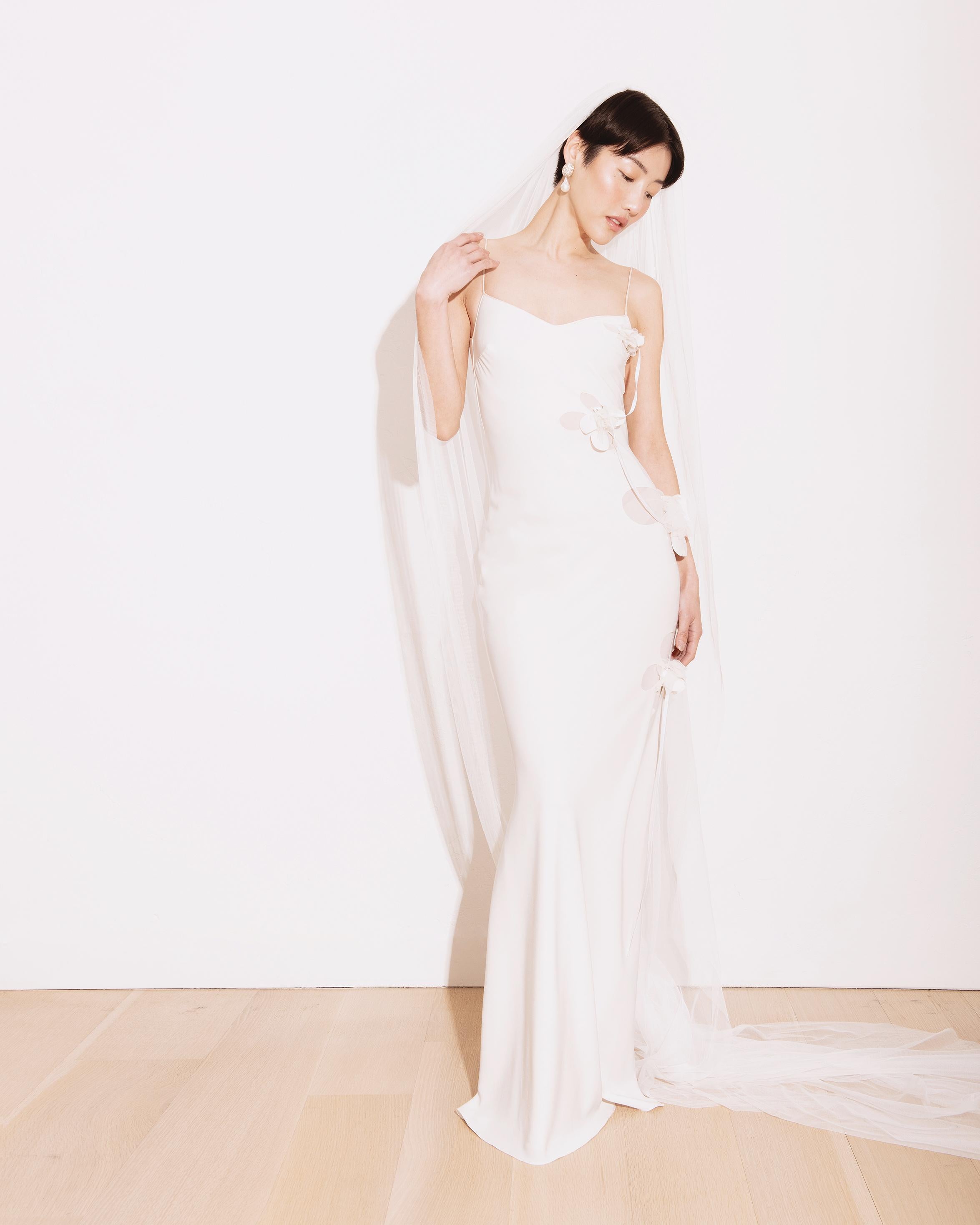 A/W 2001 John Galliano white gown with 3D floral appliques. Stunning slip gown with 3D florals draping across body, connected by white ribbon. Features unique cutout design showing light tan lining underneath openings. 