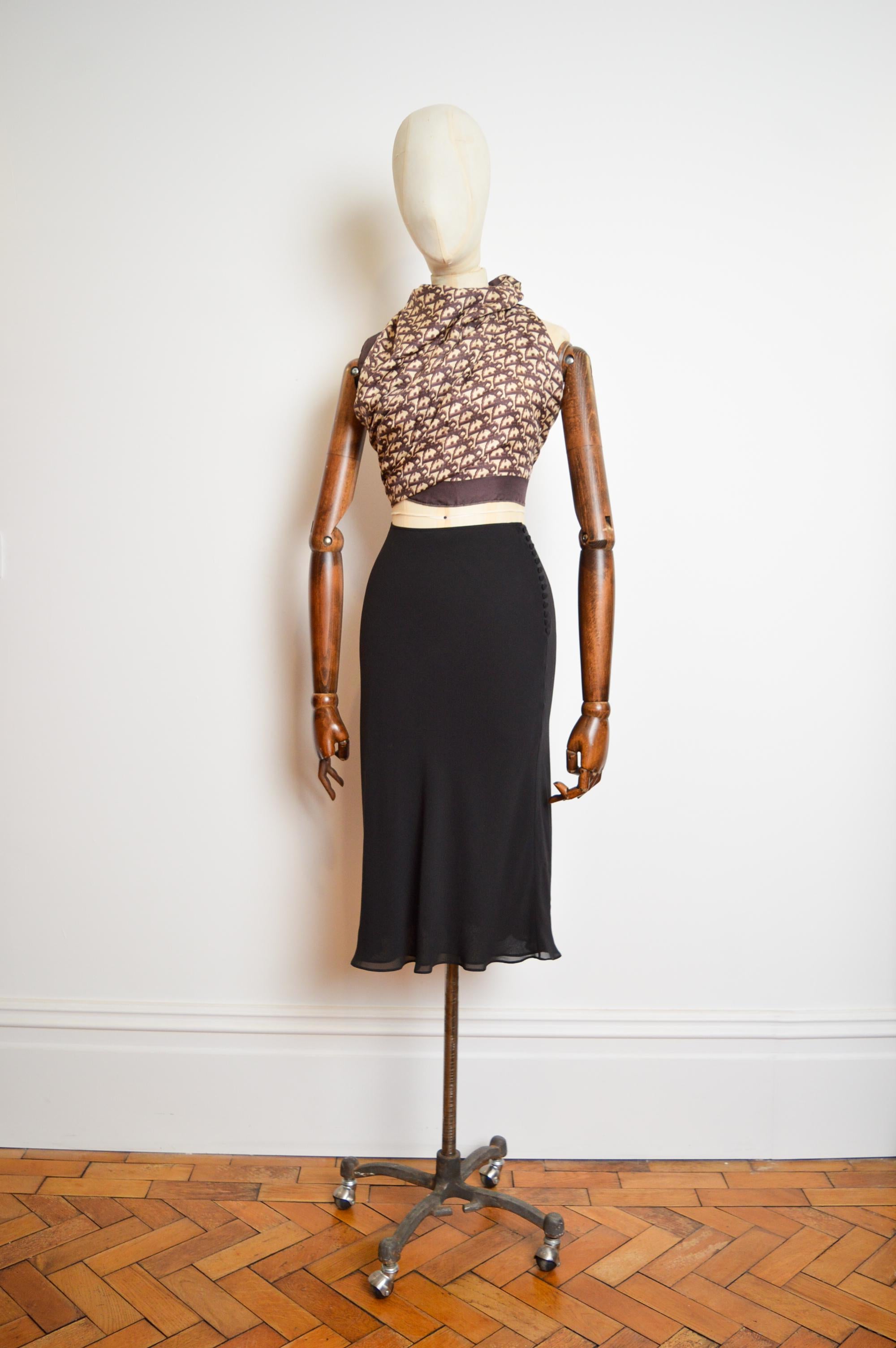 A beautiful, Timeless Autumn/ Winter 2002 CHRISTIAN DIOR by John Galliano bias cut black skirt with the typical Galliano button side details.   

MADE IN FRANCE.  

Sizing in inches; 
Waist; 25”
Length; 30”

The garment shows no visible signs of