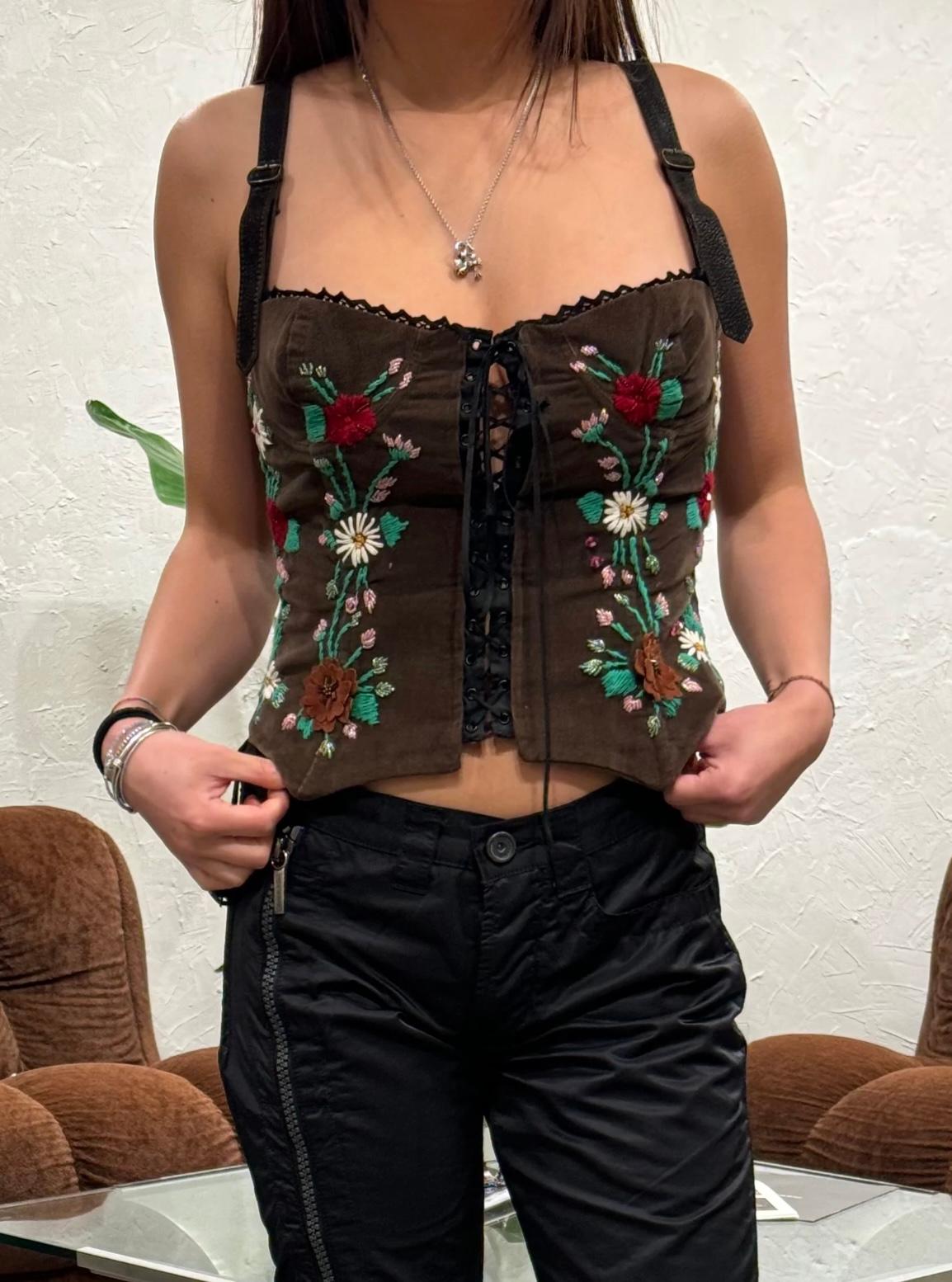 Corsetto in velluto a coste D.G. A/I 2002 con ricamo floreale

Questo raffinato corsetto della collezione Autunno/Inverno 2002 di D.G. è realizzato in lussuoso velluto a coste marrone e ornato da intricati ricami floreali dai colori vivaci. Il