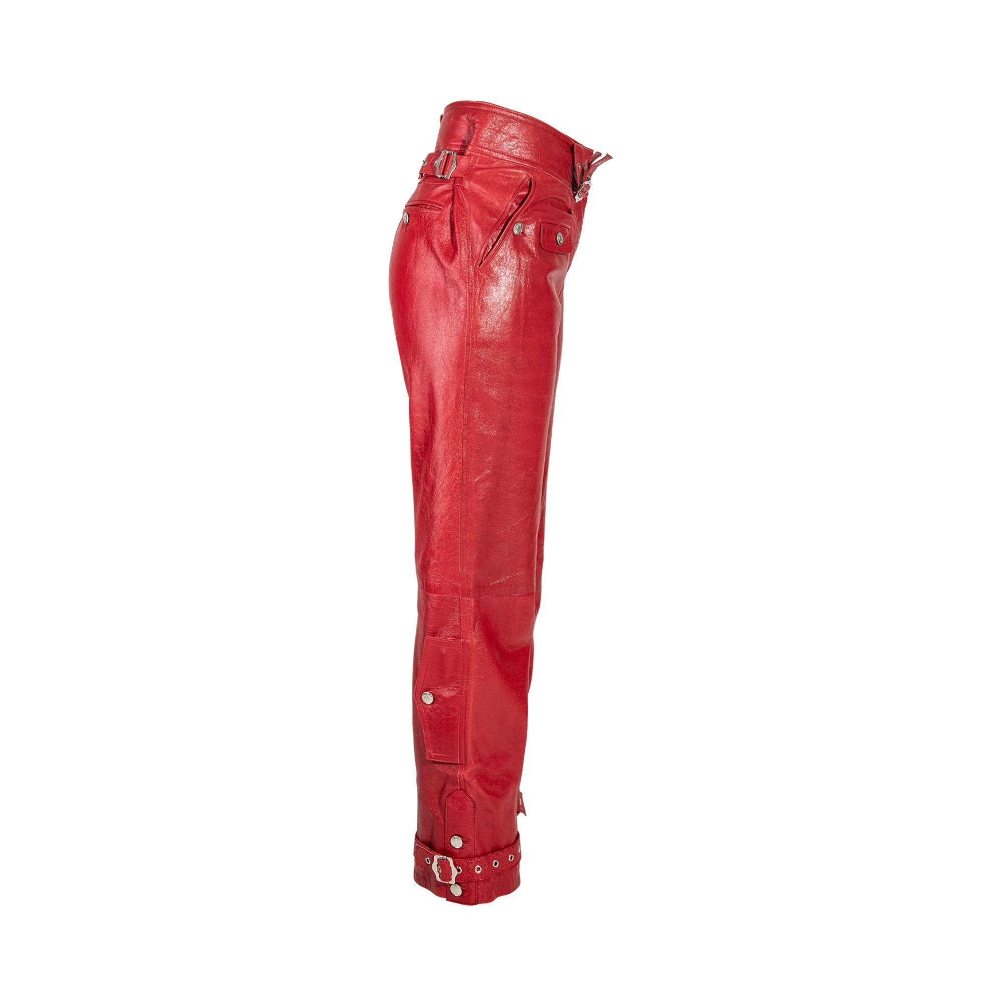 A/W 2003 Christian Dior by Galliano ‘Hard Core’ collection mid-rise red leather pants with silver details. Features silver buckle details at waist, small flap pockets and adjustable silver buckle straps around ankles. 100% Lambskin leather with 95%